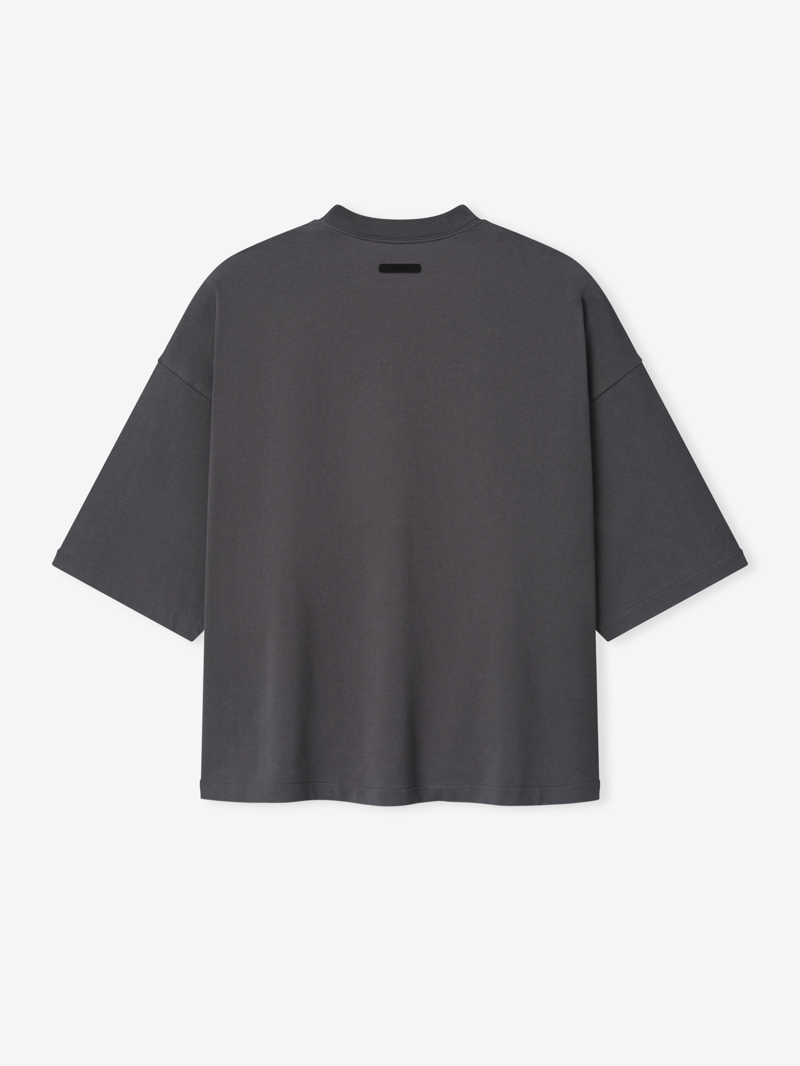 Merch Tee in dark grey featuring an oversized relaxed fit with dropped shoulders and a small black rectangular detail near the neckline for a minimalist casual top.
