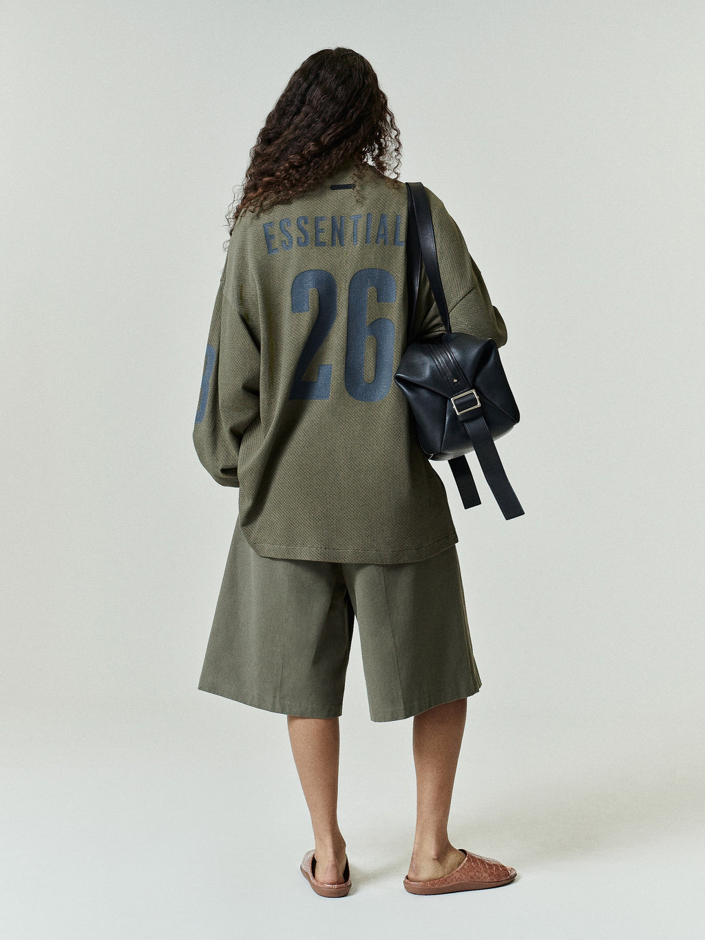 Sport Mesh Merch Long Sleeve Tee in moss green featuring bold navy "ESSENTIAL" text and large number 26 on the back, styled with matching shorts for a relaxed, sporty look.