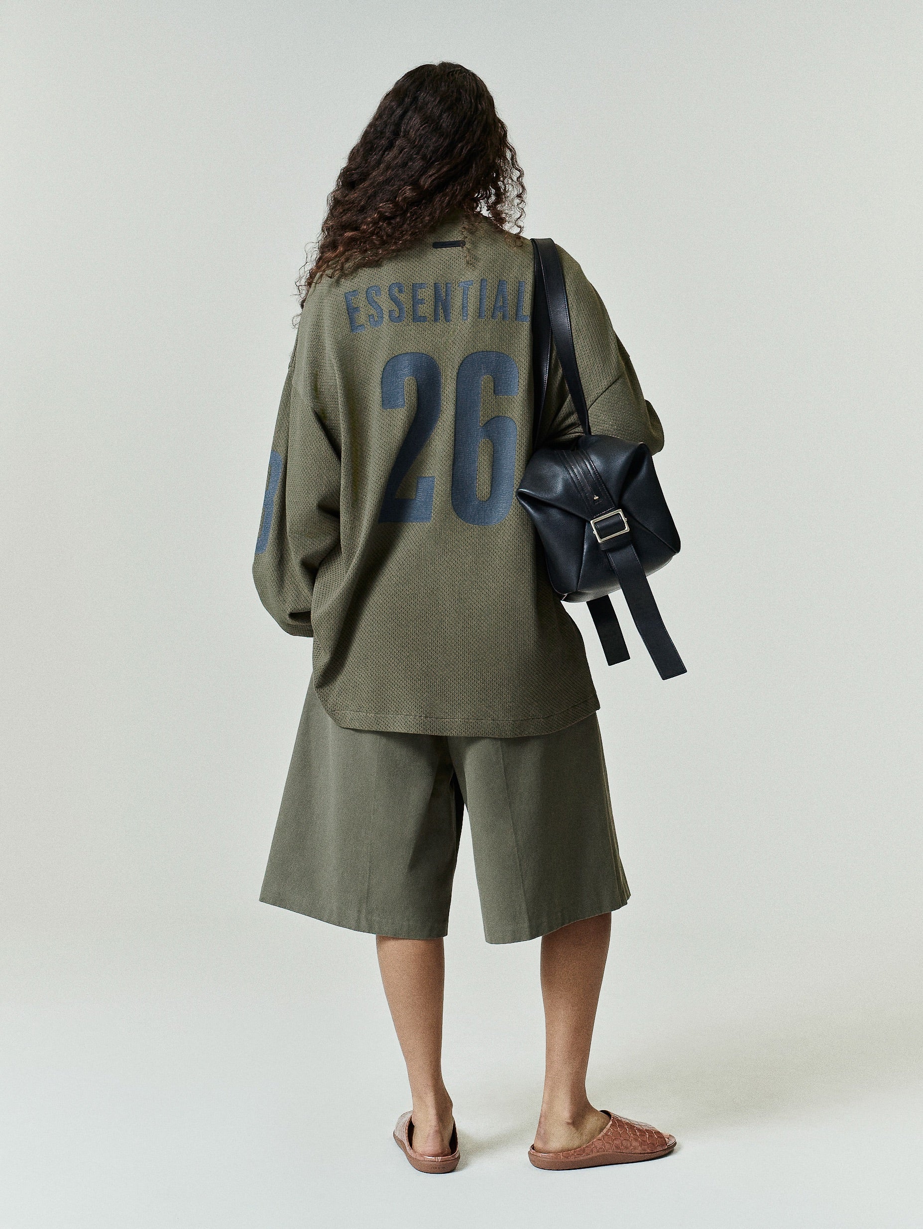 Sport Mesh Merch Long Sleeve Tee in moss green featuring bold navy "ESSENTIAL" text and large number 26 on the back, styled with matching shorts for a relaxed, sporty look.