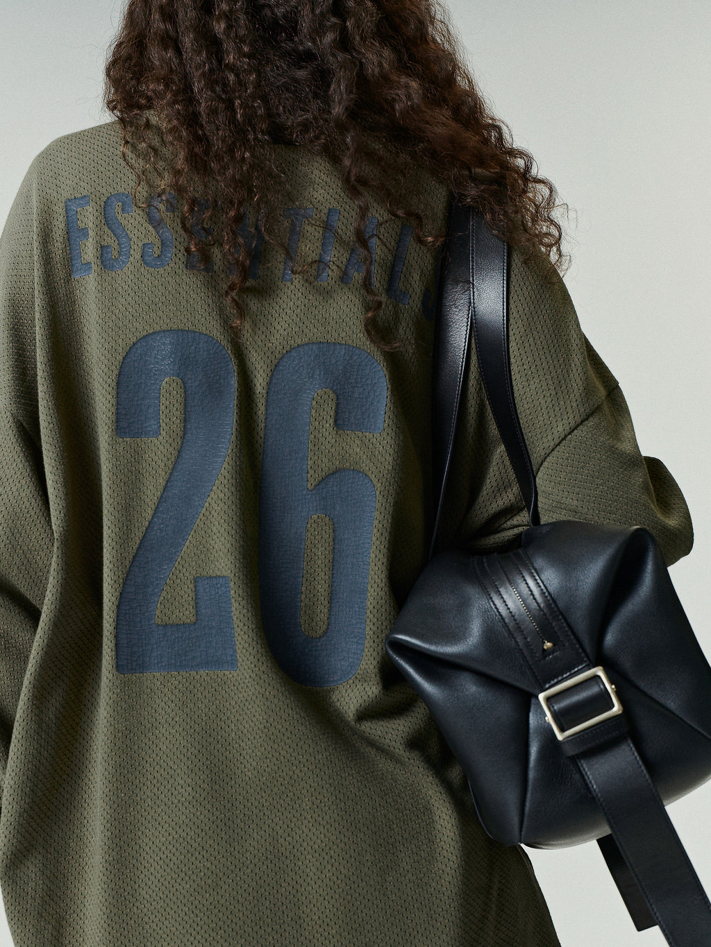 Sport Mesh Merch Long Sleeve Tee in olive green mesh fabric featuring large dark navy "ESSENTIAL" text and the number 26 on the back for a sporty, relaxed casual top.