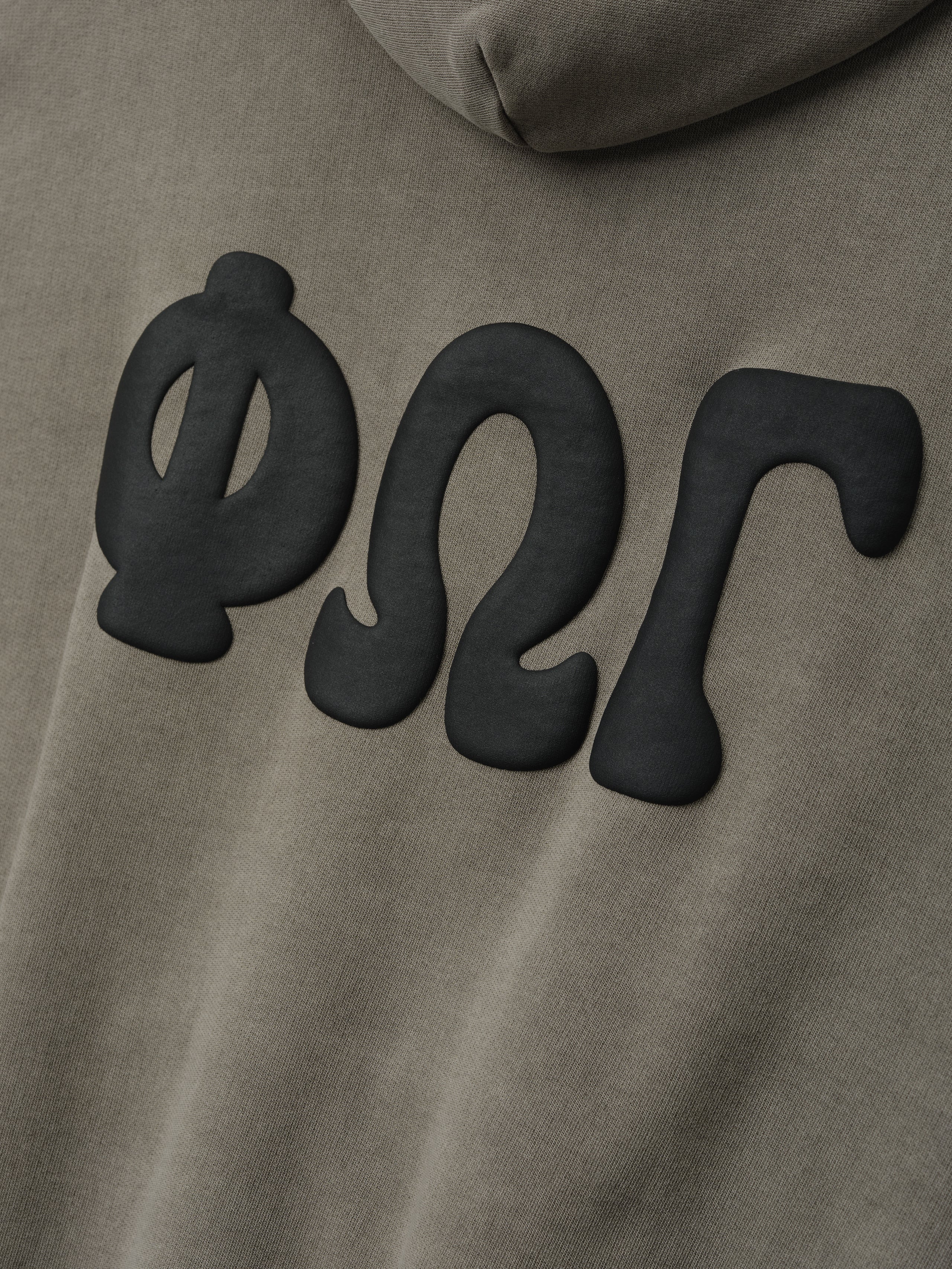 90'S Zip-Up Hoodie in a muted washed seal color featuring soft fabric with large matte black Greek letter appliqués on the back for distinctive outerwear style.