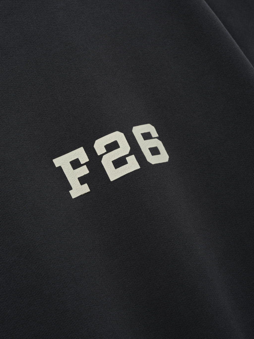 Close-up of a deep iron grey 3/4 Sleeve Crewneck showing a contrasting off-white "F 26" print, highlighting soft fabric texture and clean casual top details.