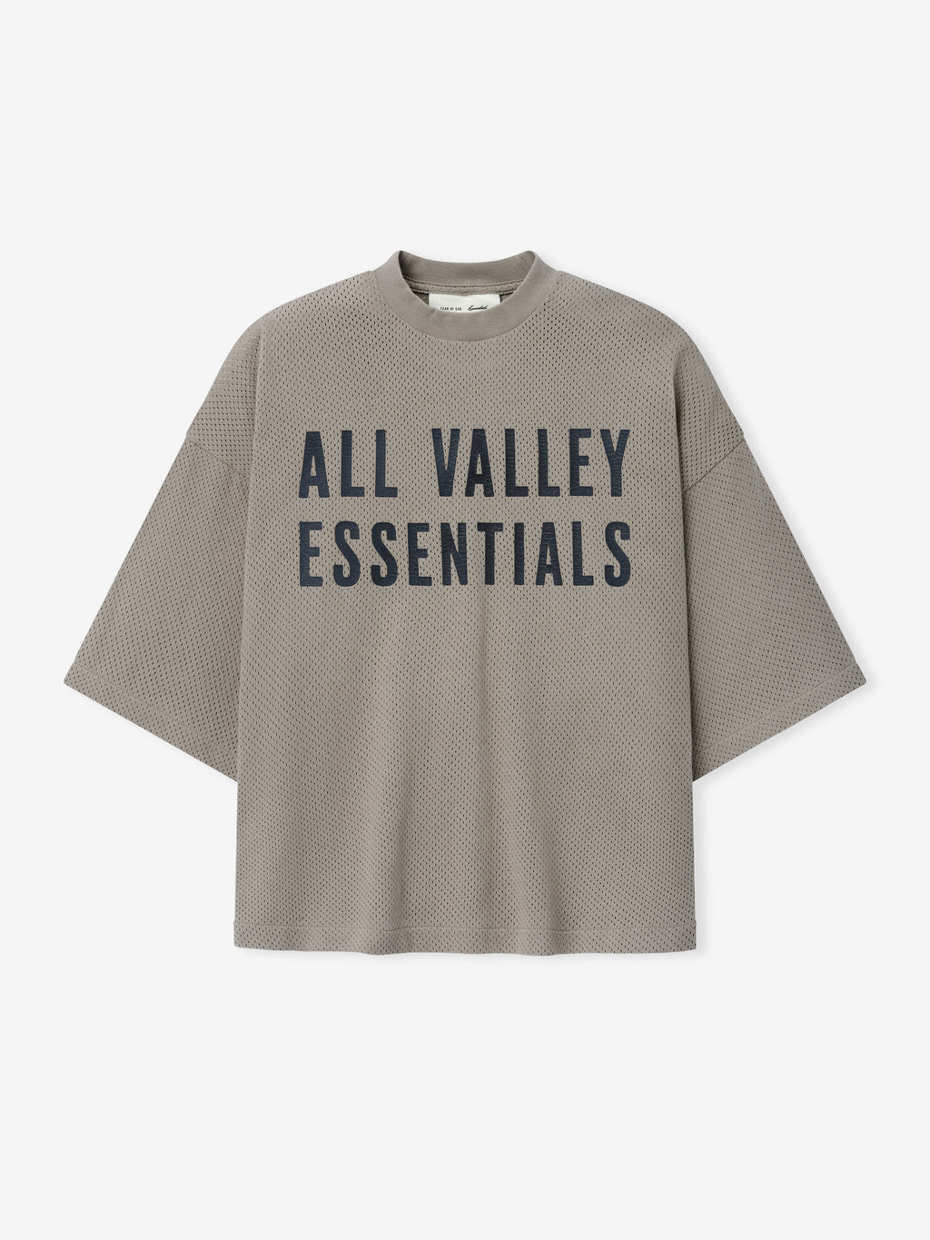 Merch Tee in muted taupe with a textured knit fabric and bold black "ALL VALLEY ESSENTIALS" text printed on the front for a modern and relaxed casual top.