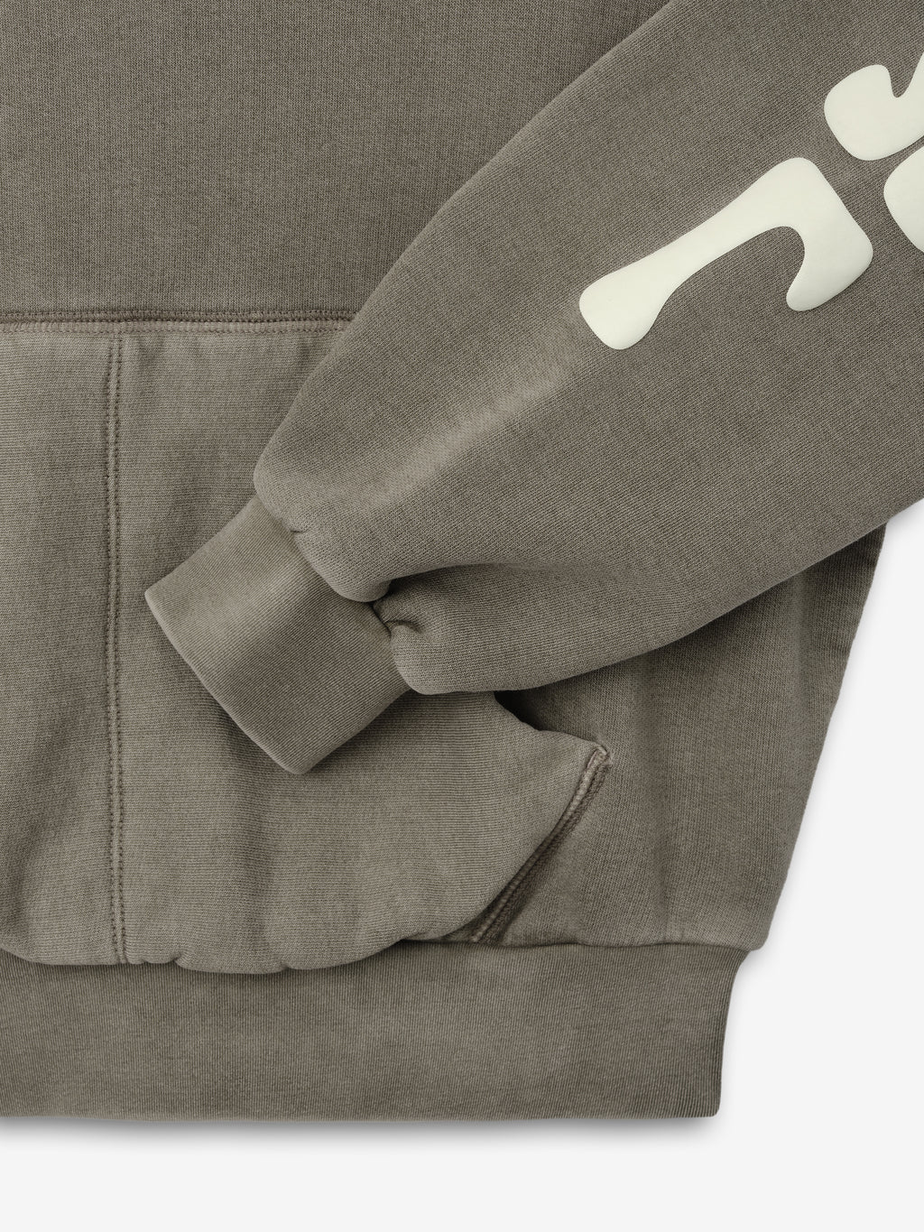 Womens 90s Fleece Hoodie in muted seal green showing close-up of the ribbed cuff, front kangaroo pocket, and part of sleeve with large cream vintage-inspired graphic lettering.