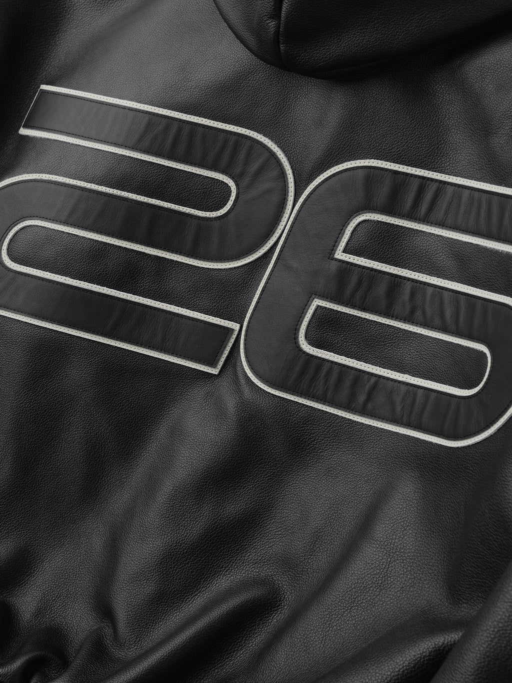 Black leather jacket with white stitching on a dark background
