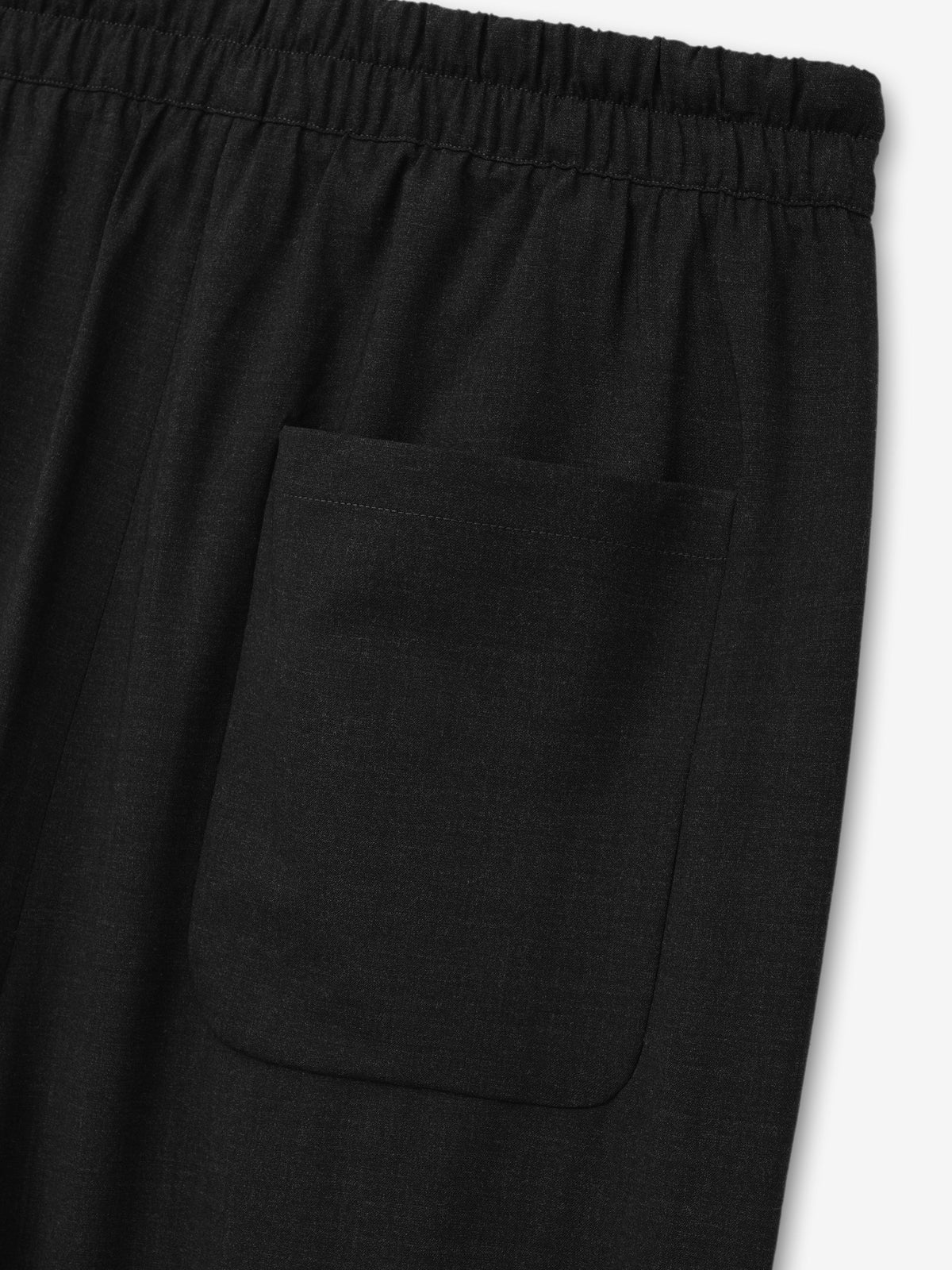 Melange Wool Box Pleat Drawstring Pants in black shown close up with an elastic waistband and large rounded patch pocket on the leg