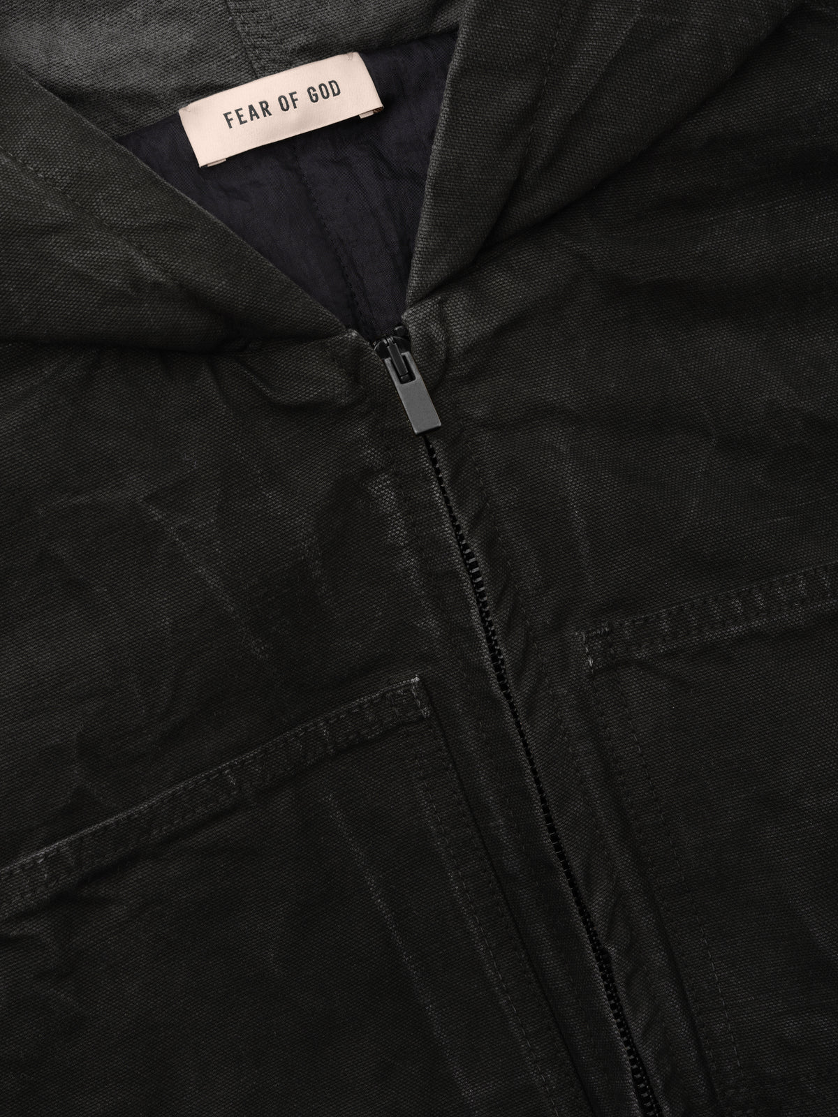 Canvas Workwear Hooded Bomber in black shown close up with a Fear of God label front zip closure hood and angled welt pockets as outerwear