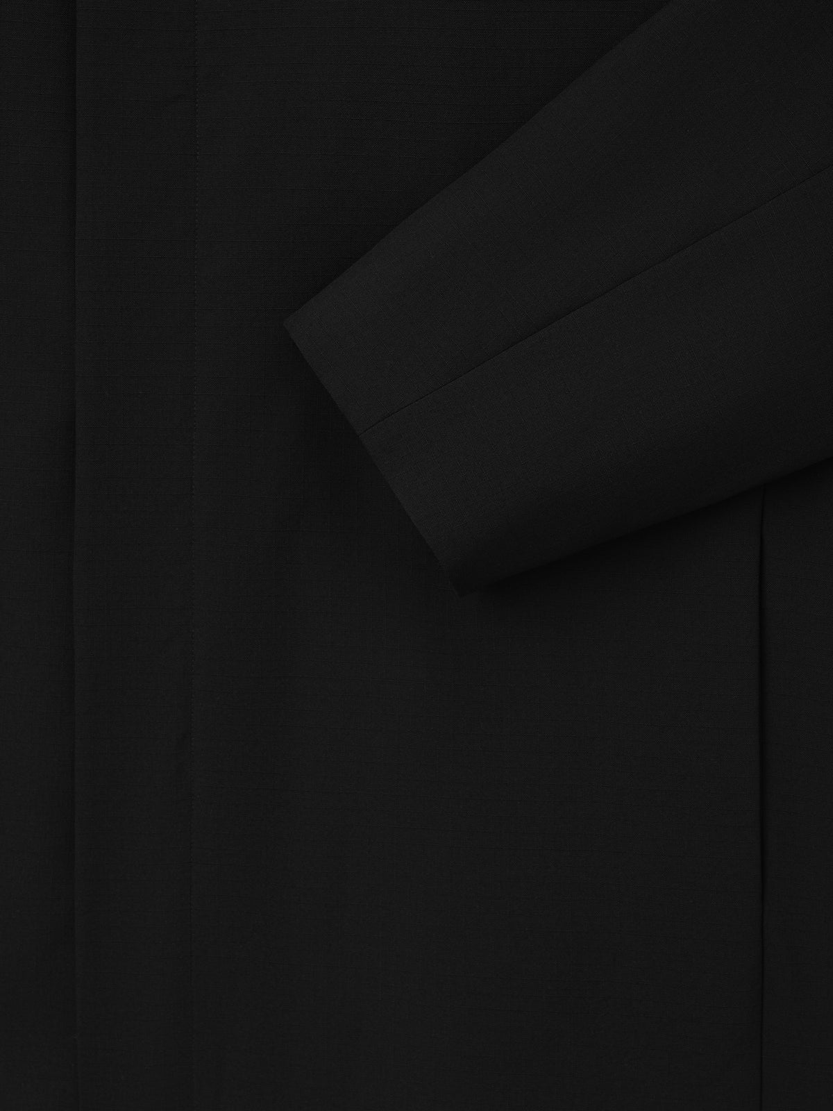 Wool Ripstop Leisure Jacket in black shown in close detail with overlapping panels and a long sleeve highlighting its subtle ripstop texture as Outerwear