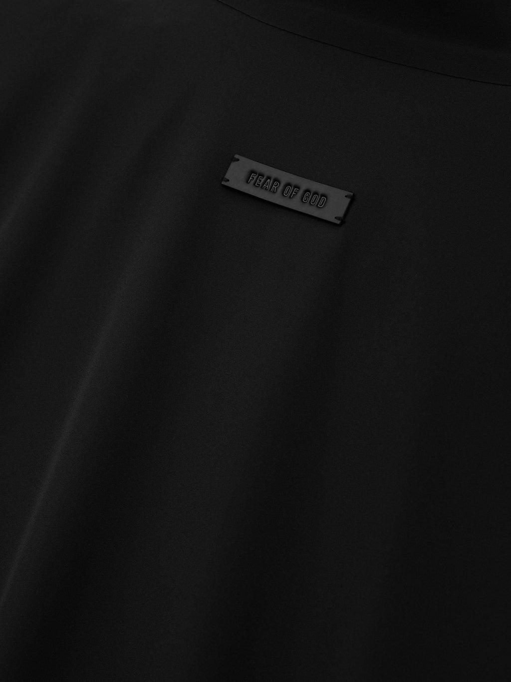 Bonded Nylon Track Jacket in black shown in close detail with a Fear of God logo plaque and smooth nylon fabric as Outerwear