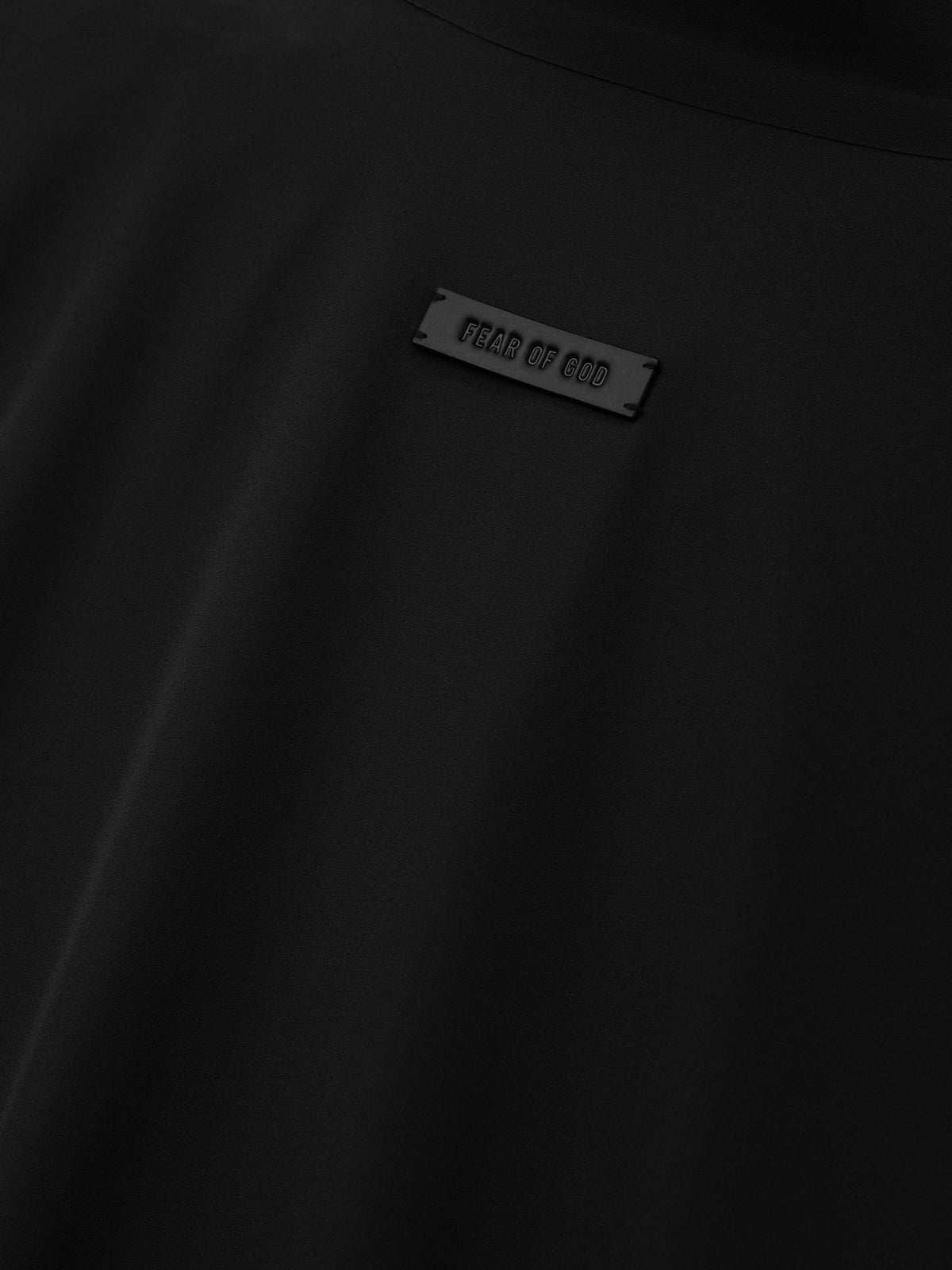 Bonded Nylon Track Jacket in black shown in close detail with a Fear of God logo plaque and smooth nylon fabric as Outerwear