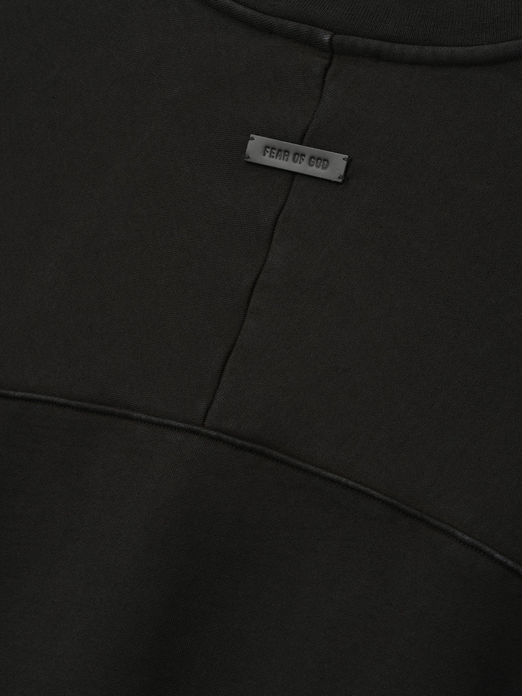 Heavy Fleece Crewneck in black shown close up with a Fear of God label and curved paneled seams across soft fleece fabric as Tops