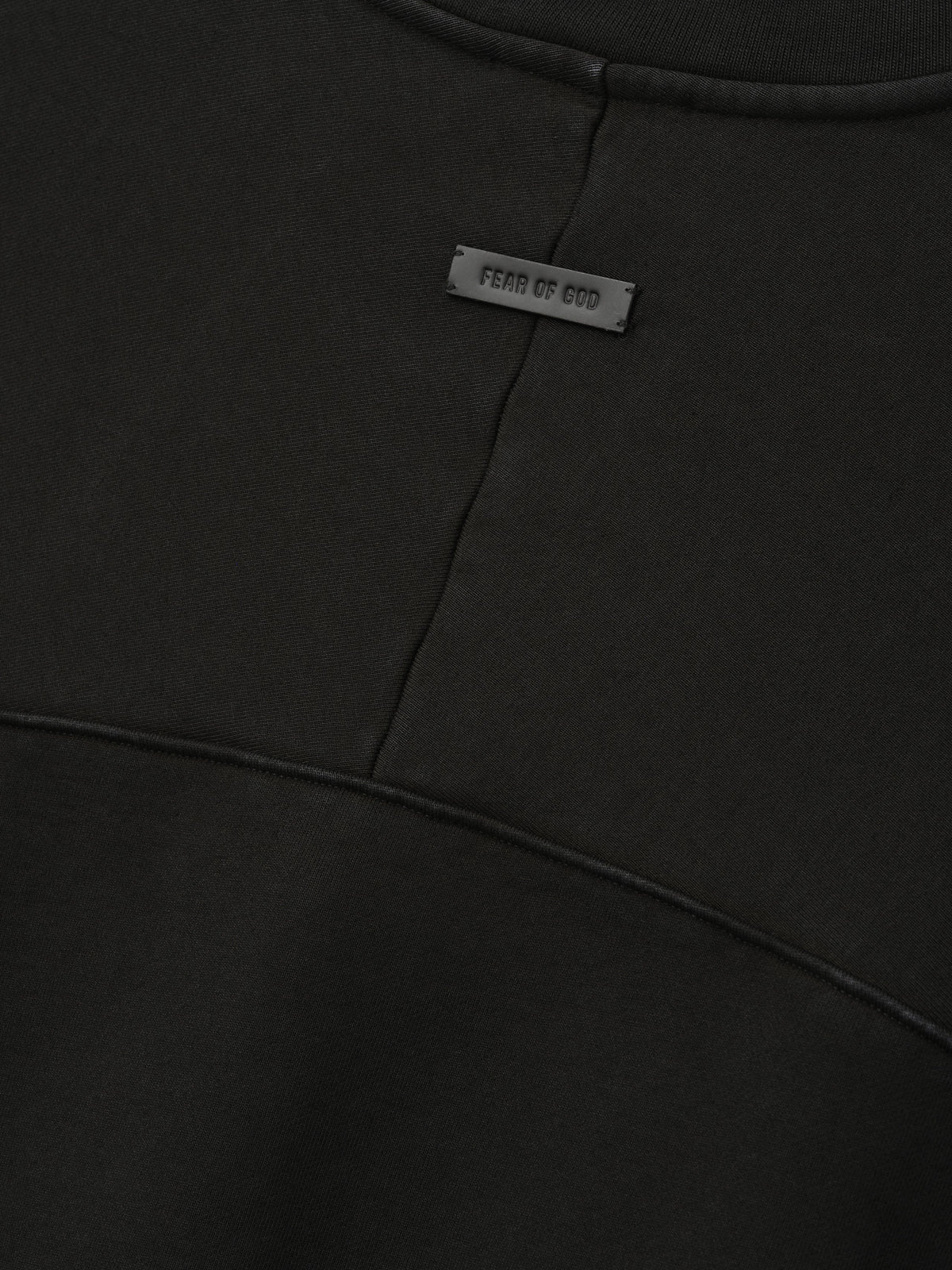 Heavy Fleece Crewneck in black shown close up with a Fear of God label and curved paneled seams across soft fleece fabric as Tops