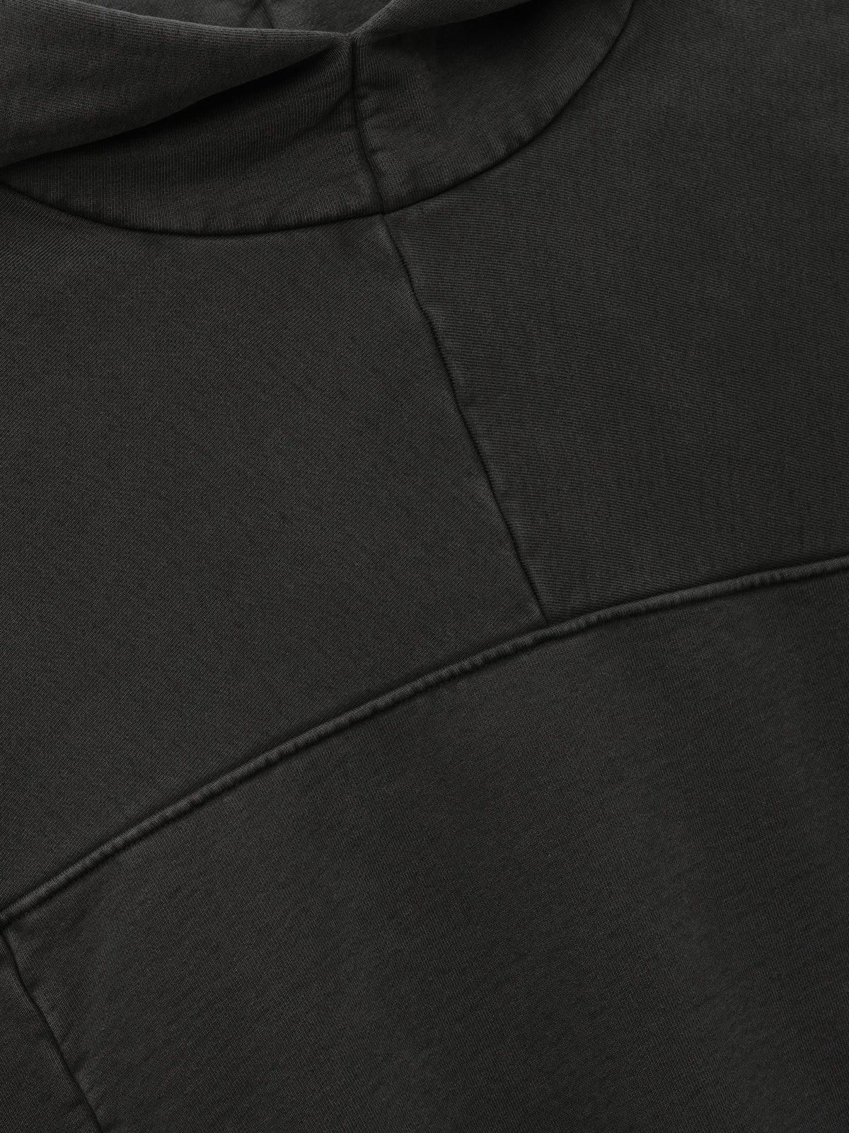 Heavy Fleece Hoodie in black shown in close detail with a curved neckline and panel seams across soft fleece fabric as Tops