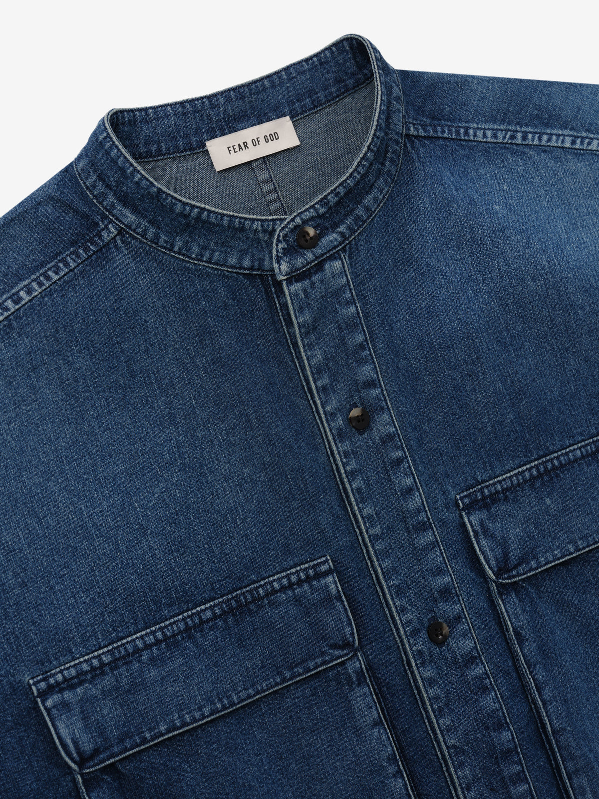 Denim Military Shirt in blue denim shown in close detail with a stand collar button front flap chest pockets and Fear of God neck label as Tops
