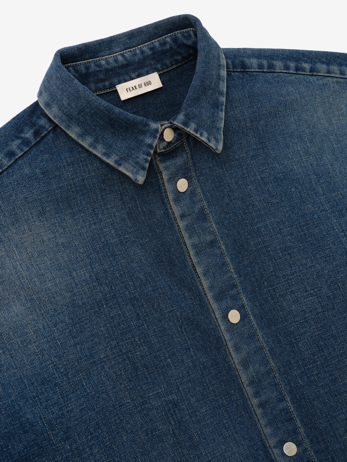 Denim Relaxed Fit Shirt in blue denim shown in close detail with a pointed collar button front metal buttons and Fear of God neck label as Tops