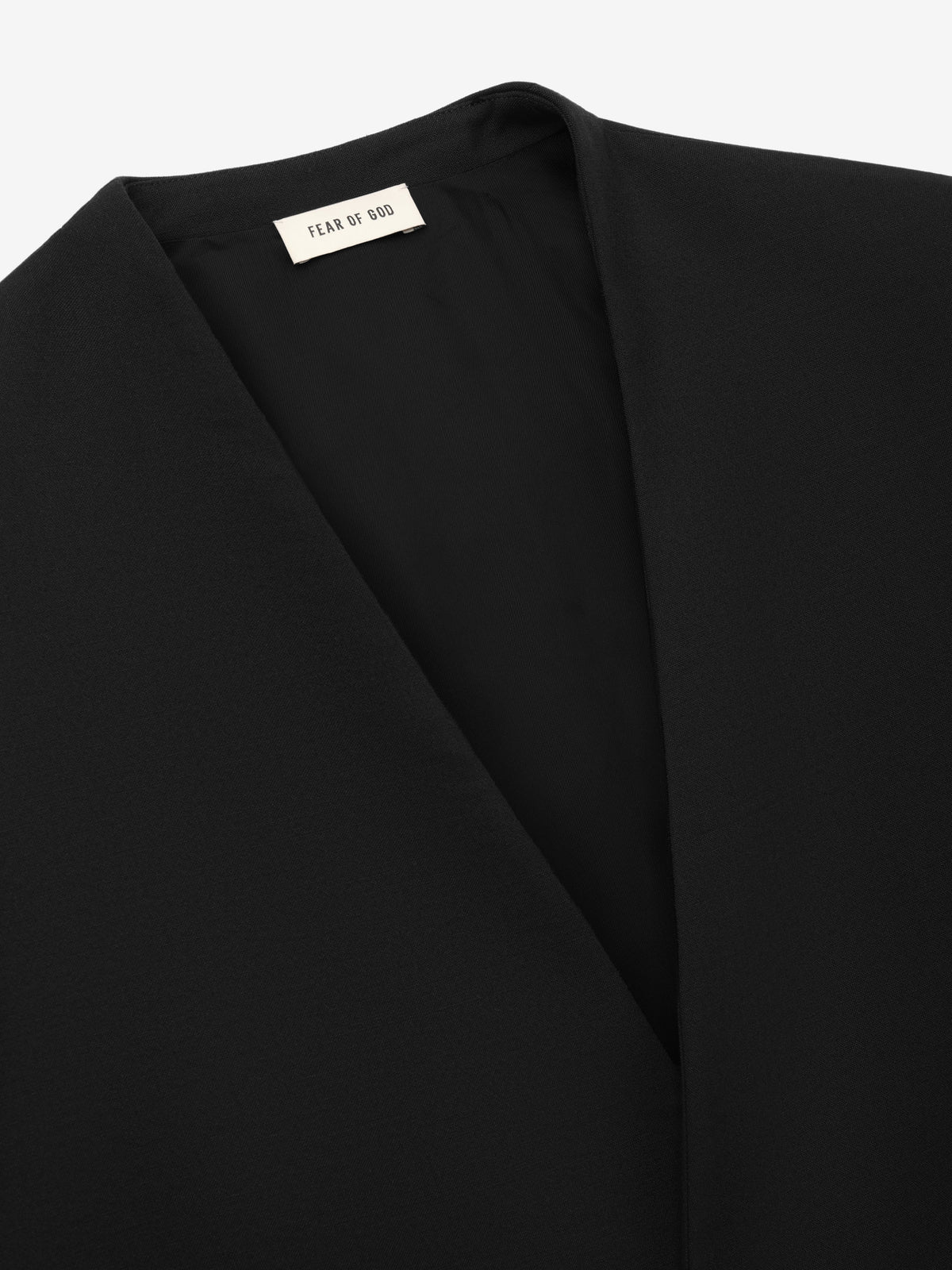 Easy Care Wool Lapelless Mid-length Jacket close up in black showing the clean lapelless neckline open front and Fear of God label as Outerwear