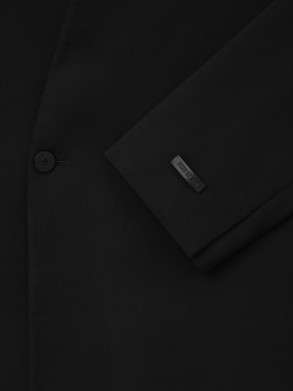 Easy Care Wool Lapelless Mid-length Jacket close up in black showing the single button sleeve detail and Fear of God label as Outerwear
