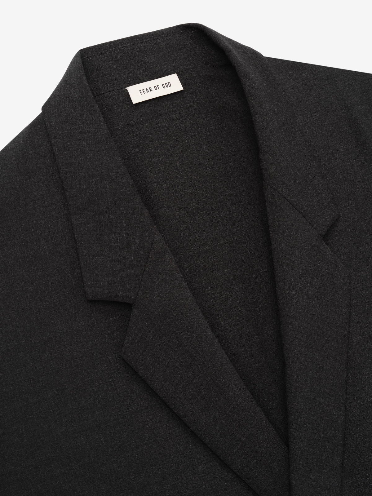 Melange Wool Relaxed Jacket in black shown close up with notch lapels and a Fear of God label highlighting its refined wool texture as Outerwear