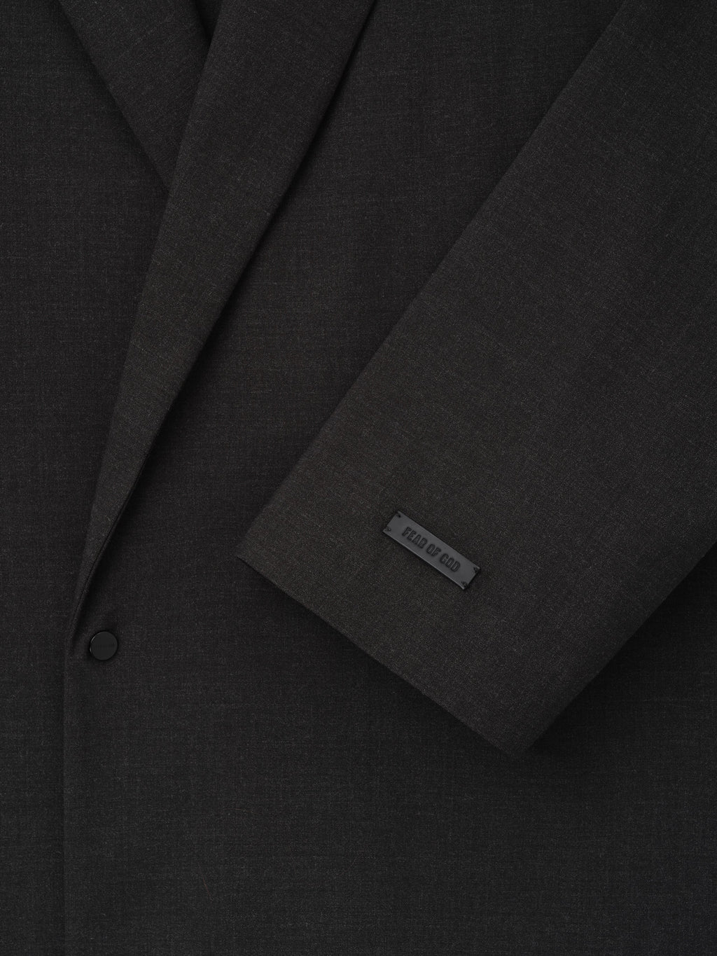 Melange Wool Relaxed Jacket close up in black showing notch lapels a button closure sleeve detail and Fear of God label as Outerwear