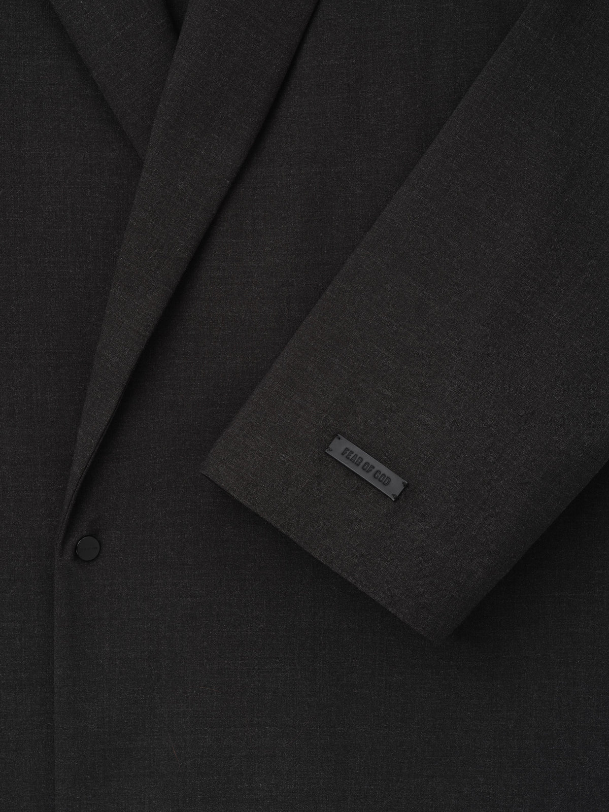 Melange Wool Relaxed Jacket close up in black showing notch lapels a button closure sleeve detail and Fear of God label as Outerwear