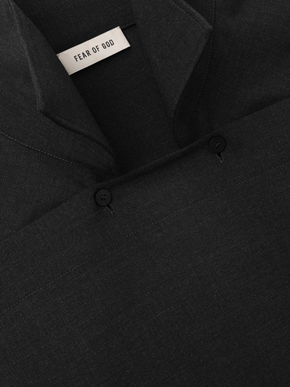 Melange Wool Pullover Shirt close up in black showing the overlapping neckline two button closure and Fear of God label with a refined wool texture as Tops
