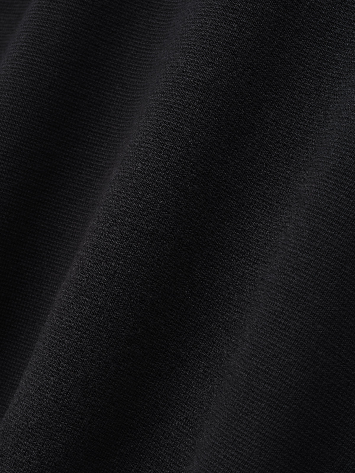 Merino Knit Mockneck Sweater close up in black revealing its fine knit texture and softly draped fabric as Tops