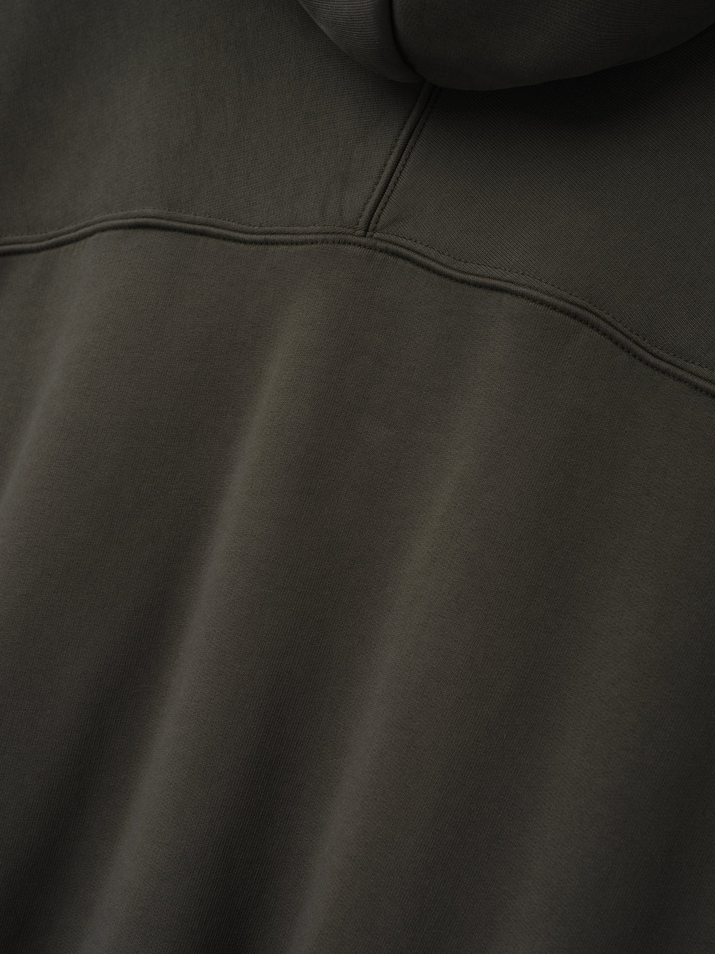 Raglan Hoodie in dark gray shown close up with a curved chest yoke seam and soft fleece texture across the front as Tops