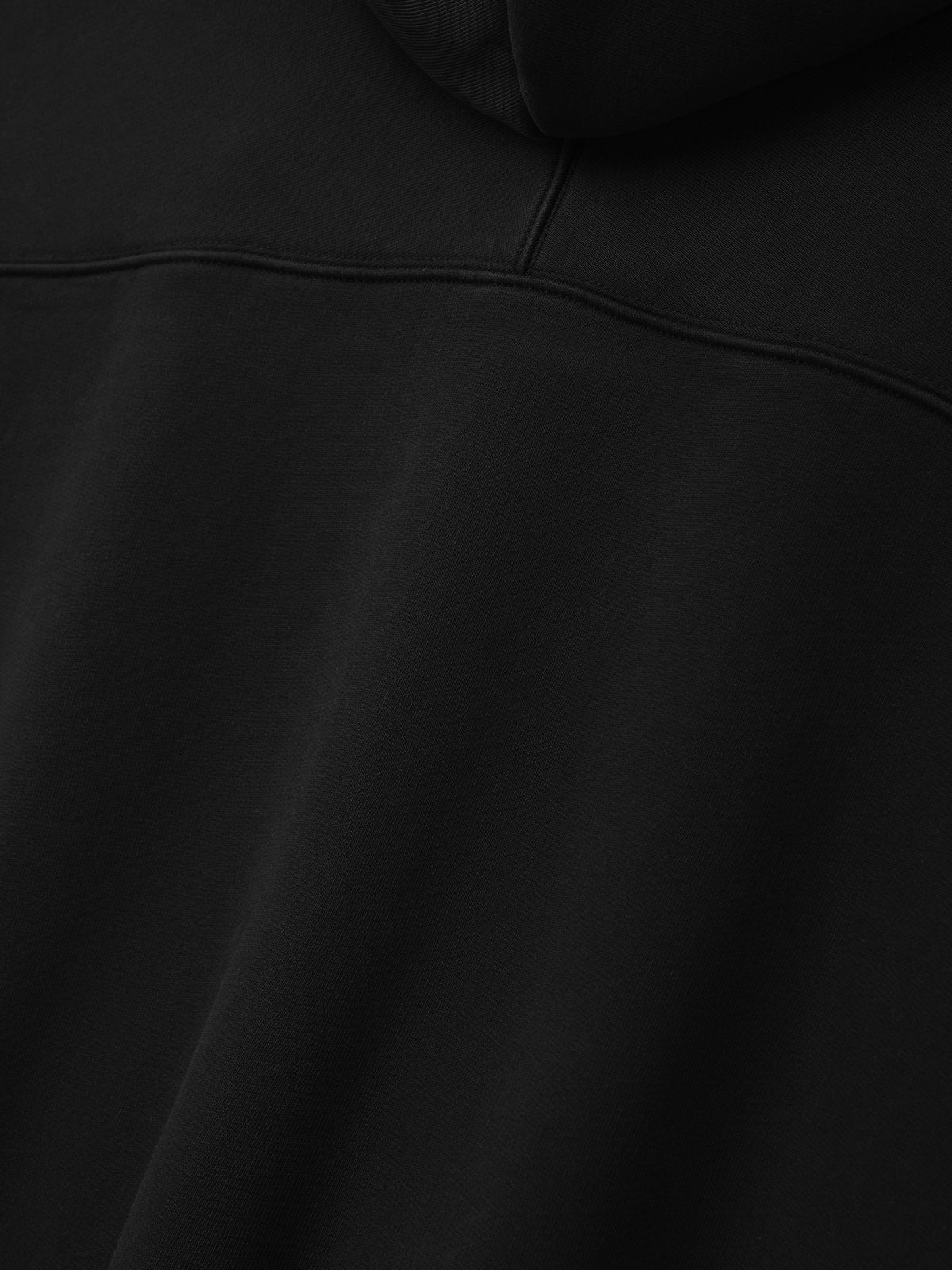 Raglan Full Zip Hoodie in black shown in close detail with a curved yoke seam and smooth fleece texture as Tops