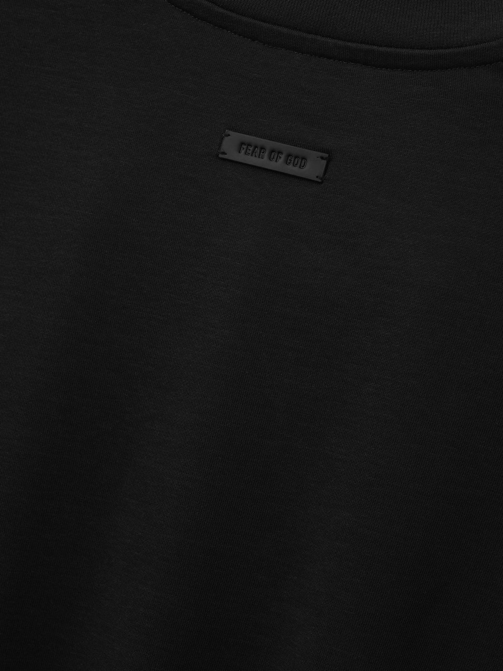 Cotton Rayon Eternal Tee in black shown in close detail with crewneck collar smooth fabric and Fear of God label as Tops