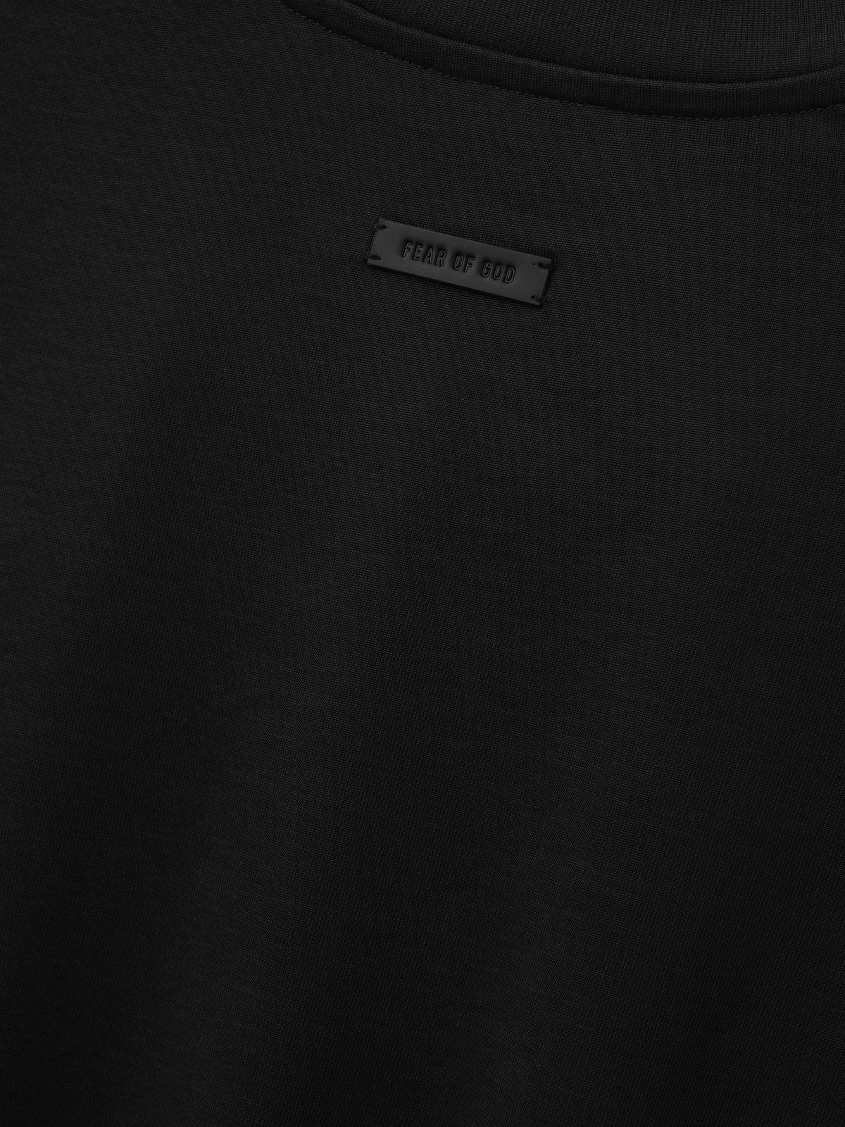 Cotton Rayon Eternal Tee in black shown in close detail with crewneck collar smooth fabric and Fear of God label as Tops