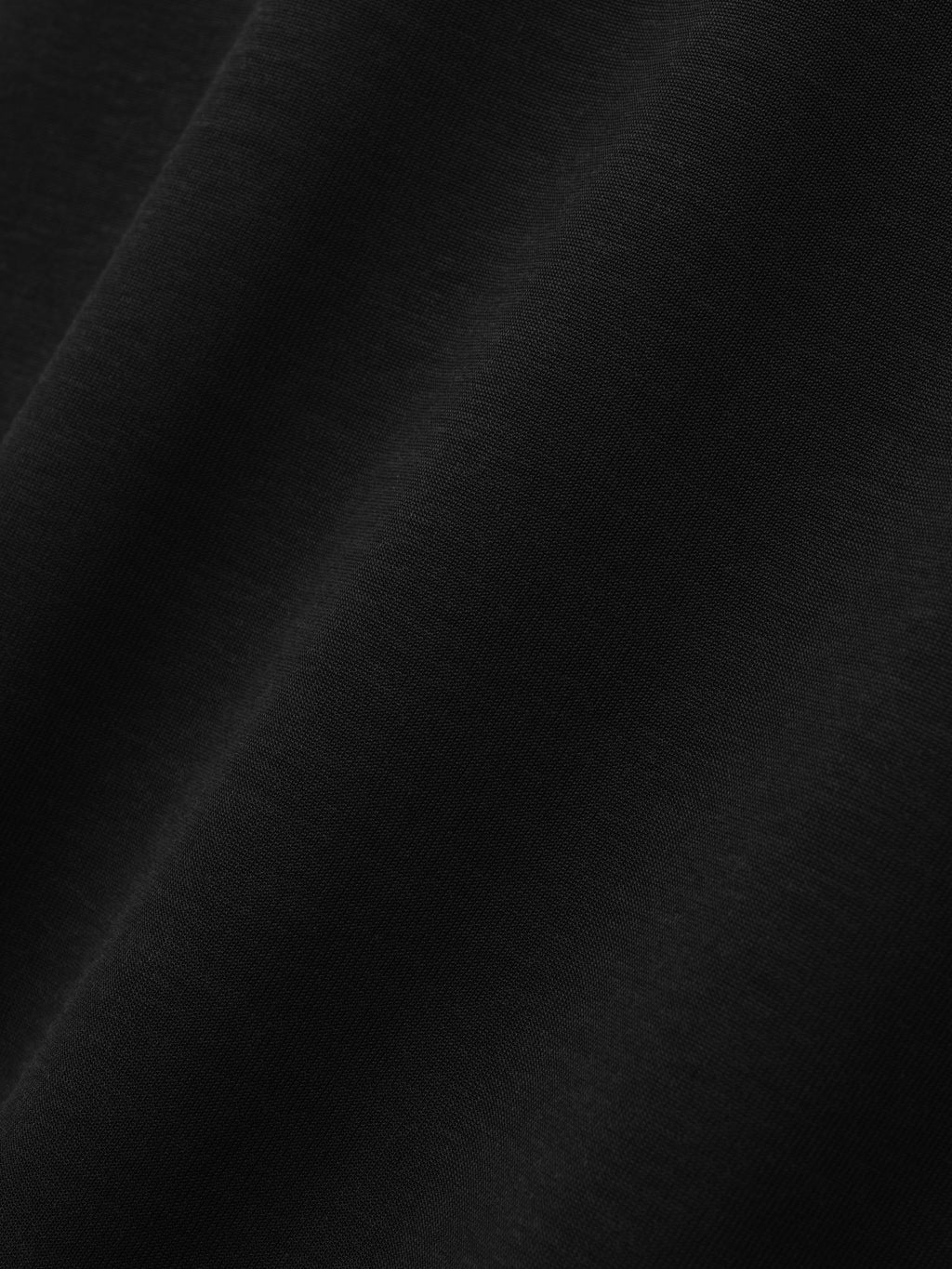 Cotton Rayon Eternal Tee in black shown in close detail with smooth cotton rayon fabric and subtle folds as Tops