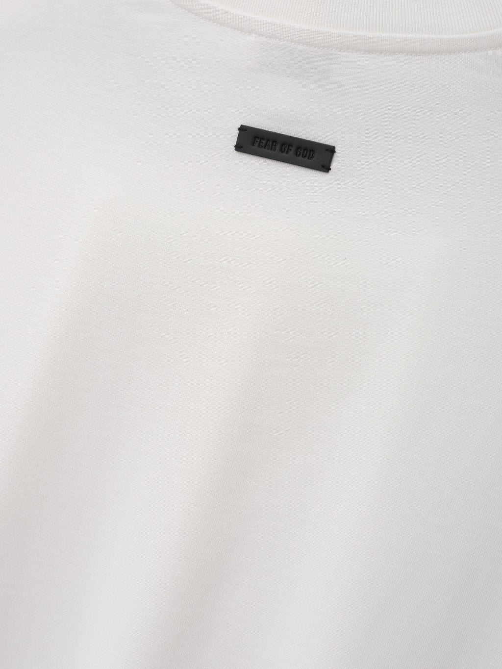 Cotton Rayon Eternal Tee in off white shown in close detail with smooth fabric crewneck collar and Fear of God label as Tops