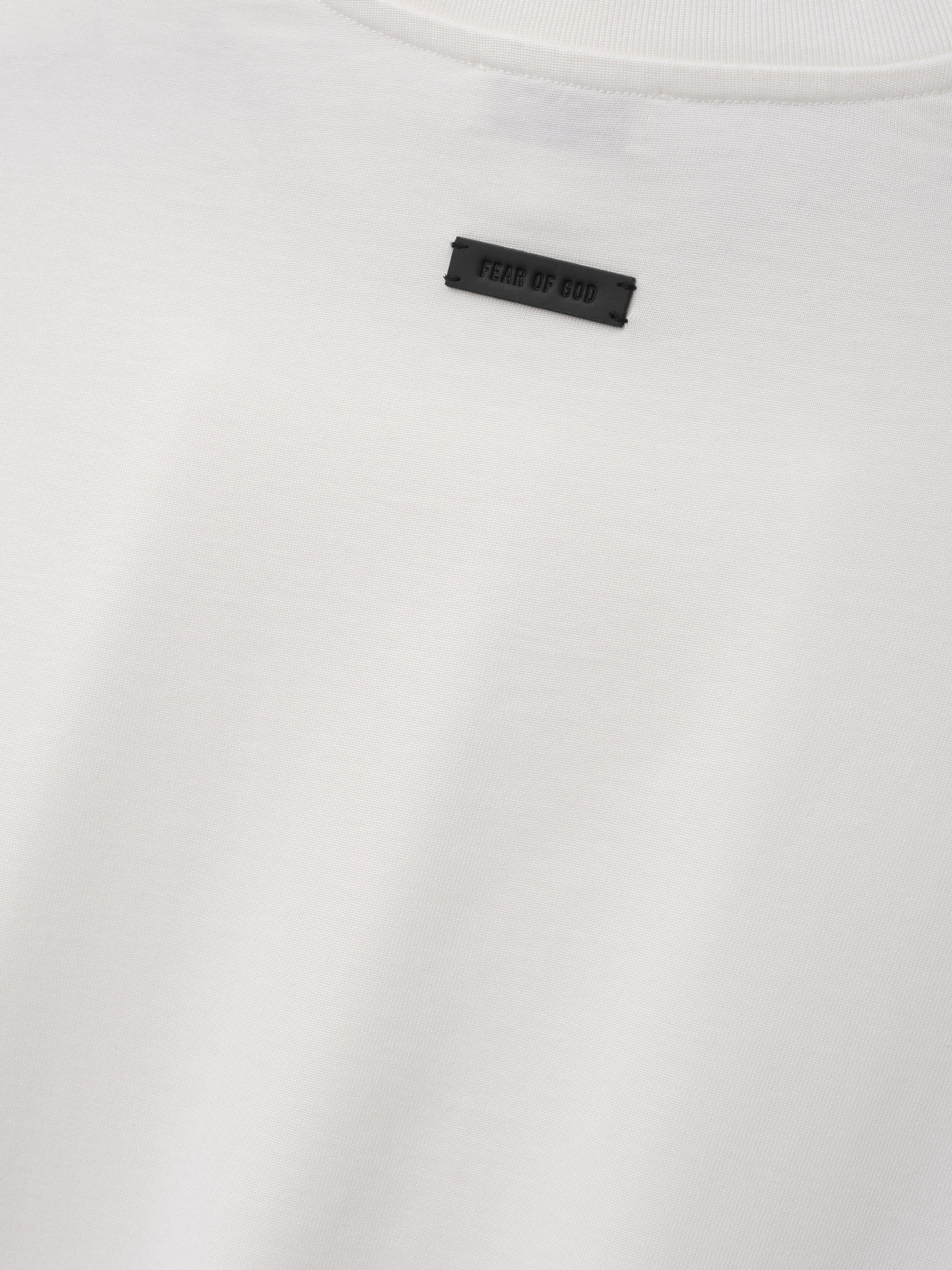Cotton Rayon Eternal Tee in off white shown in close detail with smooth fabric crewneck collar and Fear of God label as Tops