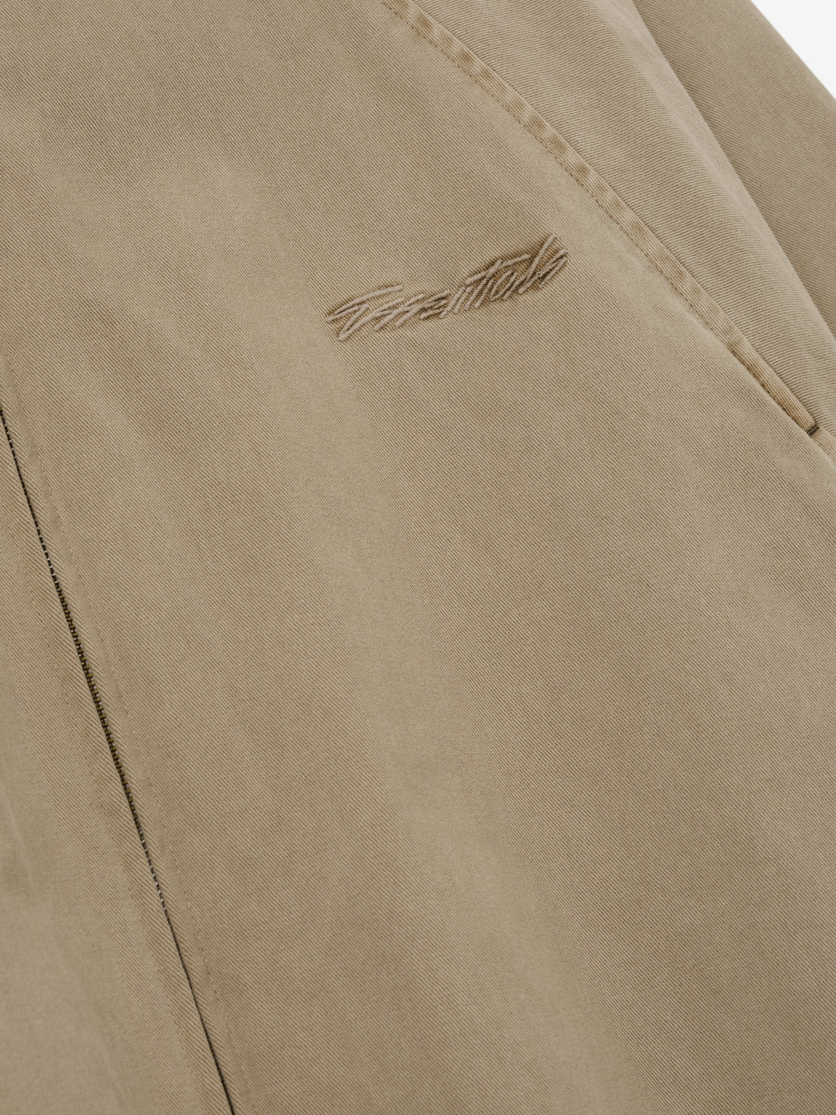 Cotton Twill Modern Filled Jacket closeup in taupe showing textured cotton twill fabric angled pocket and embroidered Fear of God logo as Outerwear