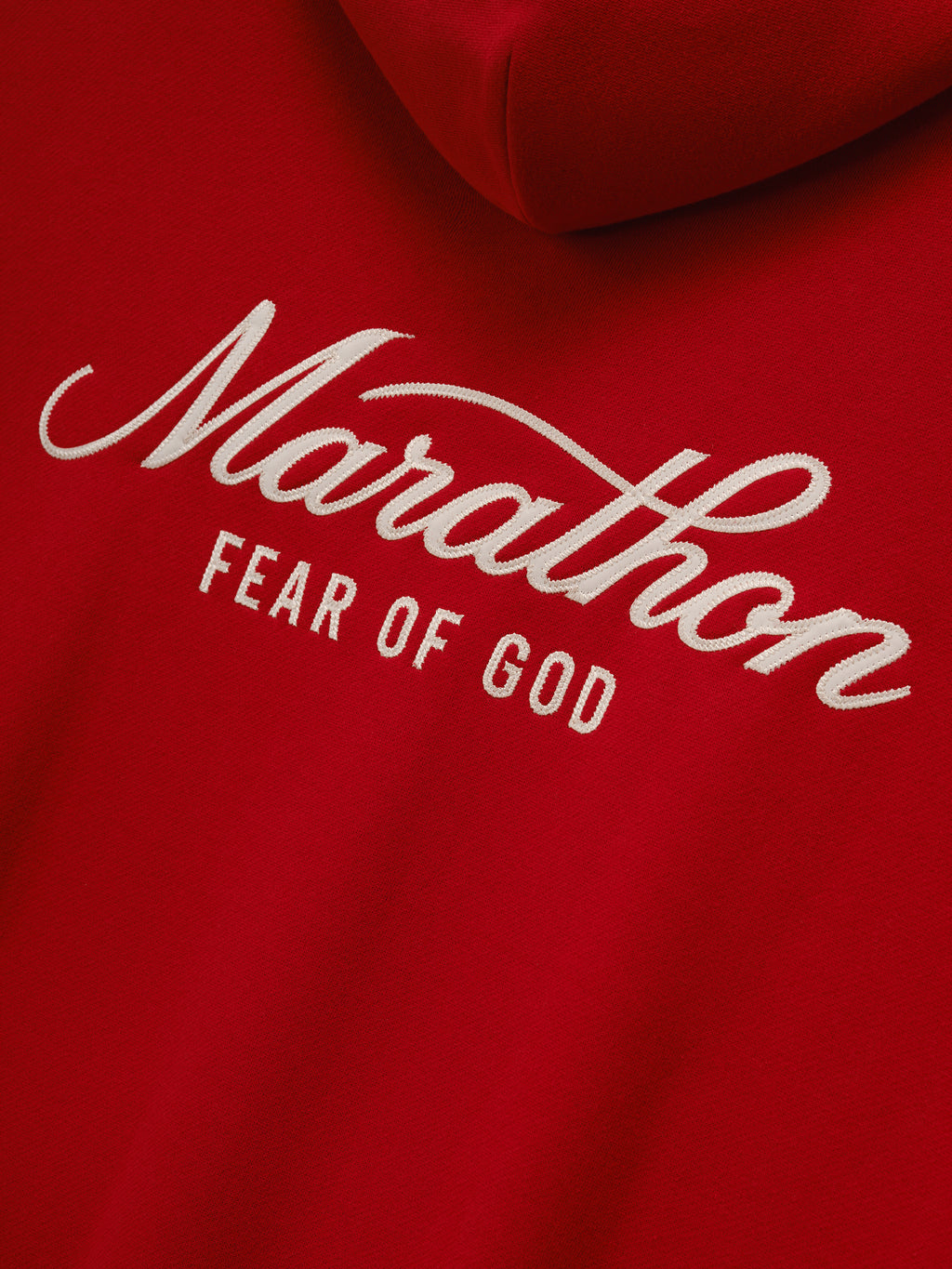 Marathon Merch Hoodie in red shown in close detail with white Marathon Fear of God embroidered chest lettering on soft fleece fabric as Tops