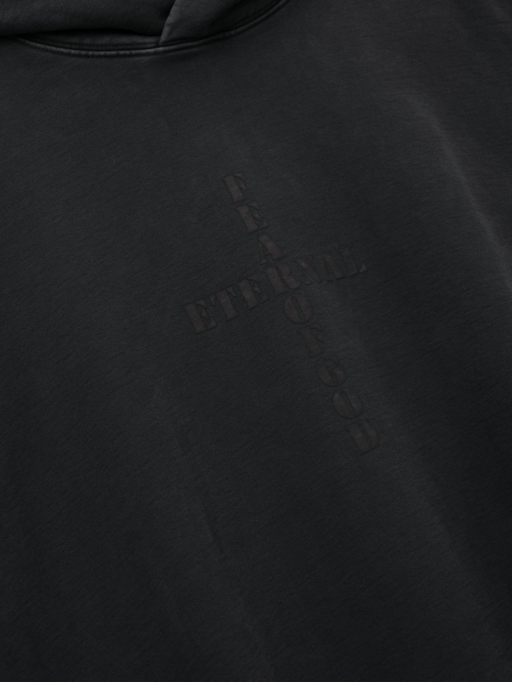 Cross Hoodie shown in close detail in black with a subtle tonal cross graphic on smooth fabric as Tops