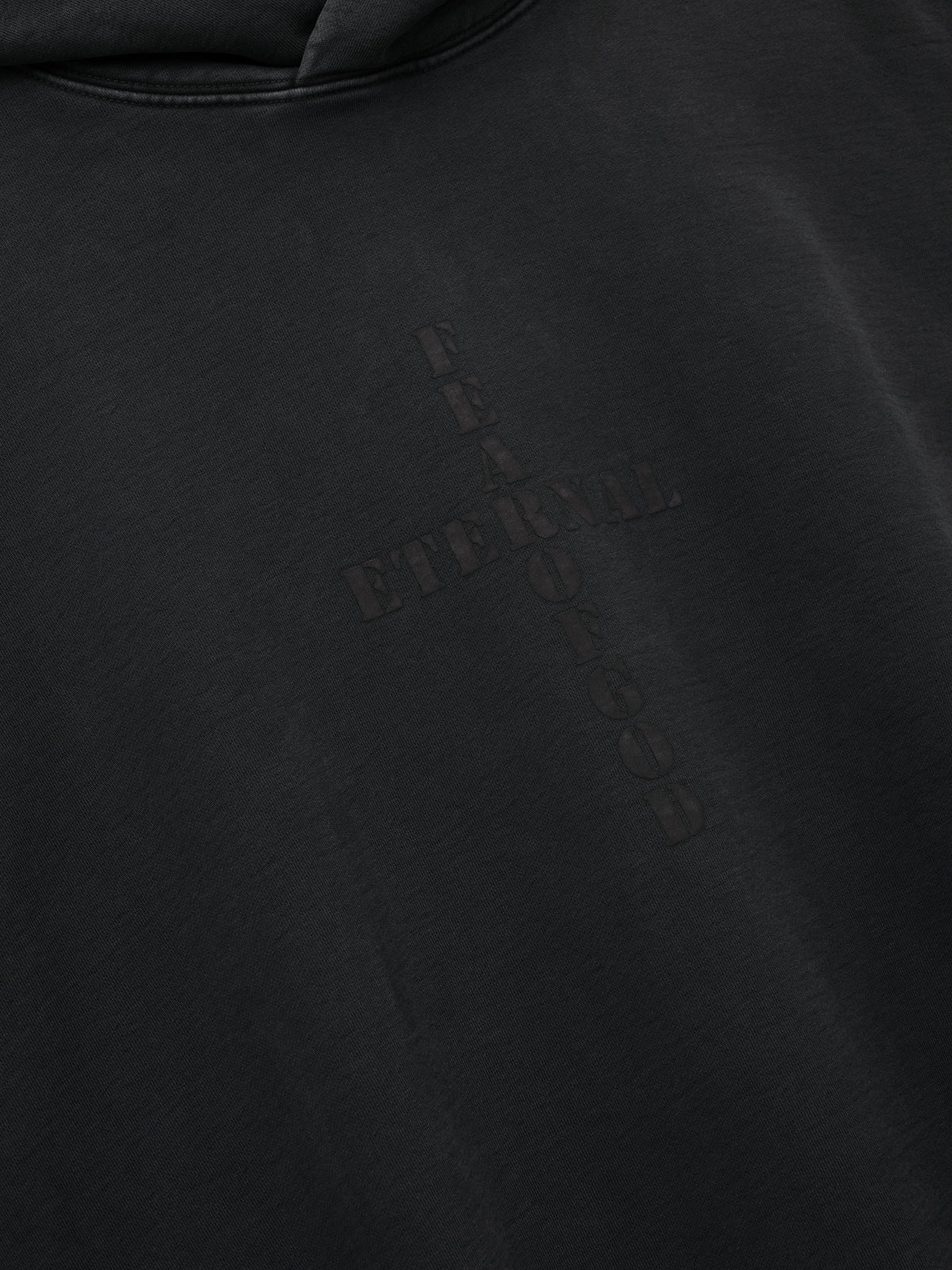 Cross Hoodie shown in close detail in black with a subtle tonal cross graphic on smooth fabric as Tops