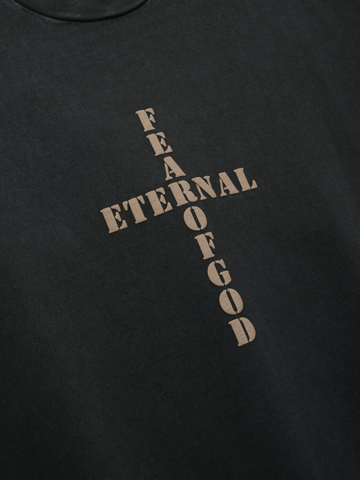 Cross Tee shown in close detail in black with ETERNAL OF GOD lettering arranged in a cross on the chest as Tops