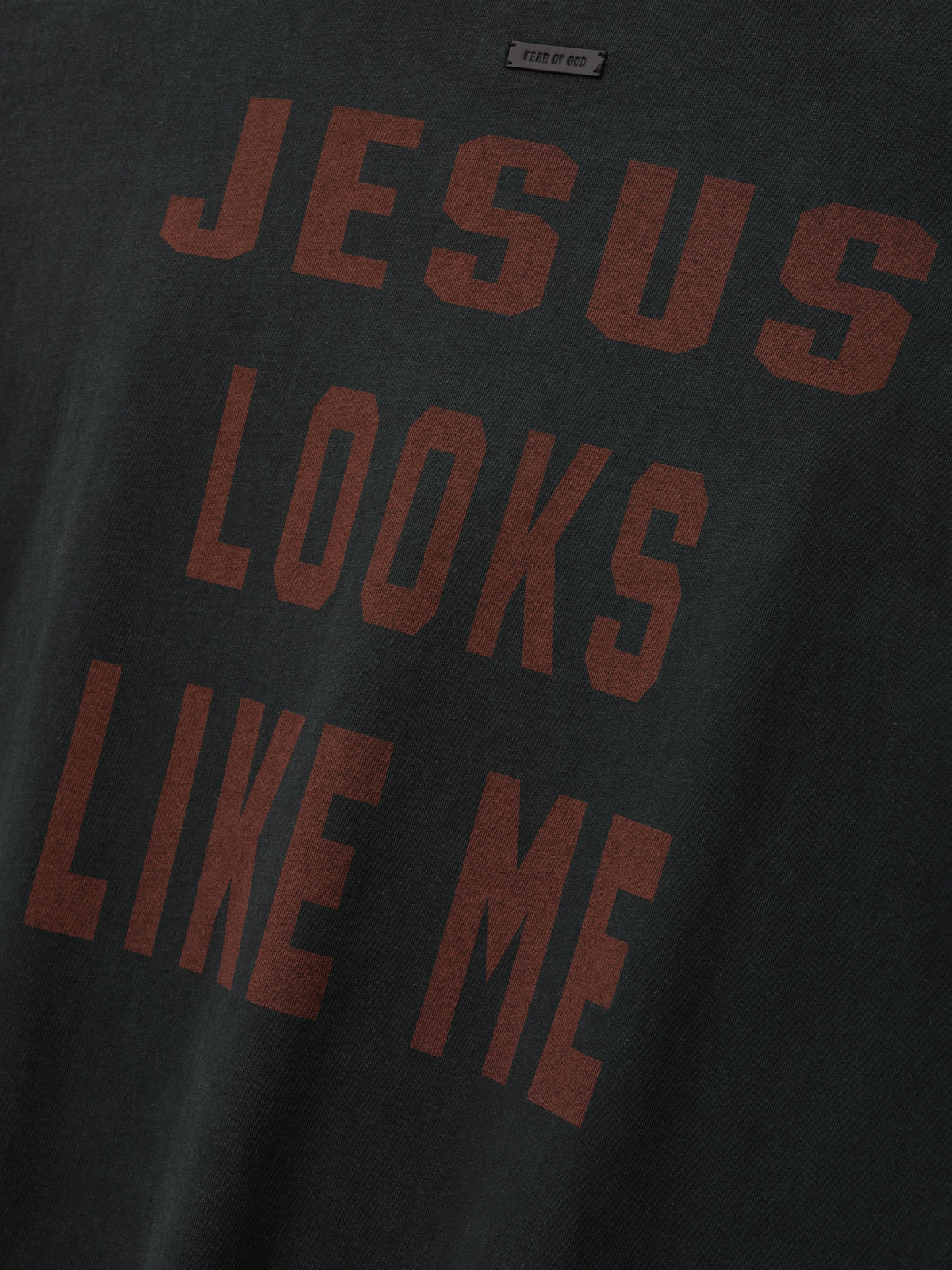 Cross Tee shown in close detail in black with bold burgundy JESUS LOOKS LIKE ME lettering on the chest and a visible neck label as Tops