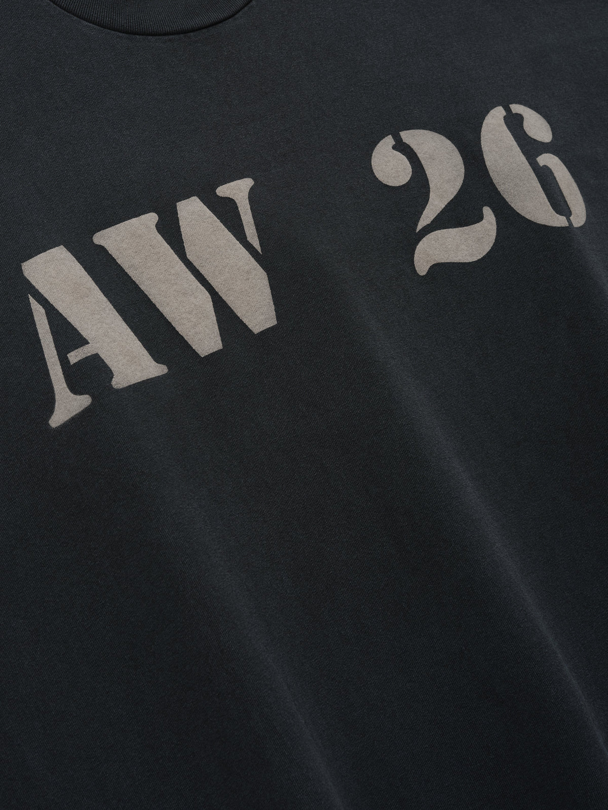AW26 Tee in black with tonal gray AW 26 chest lettering shown in close detail as Tops