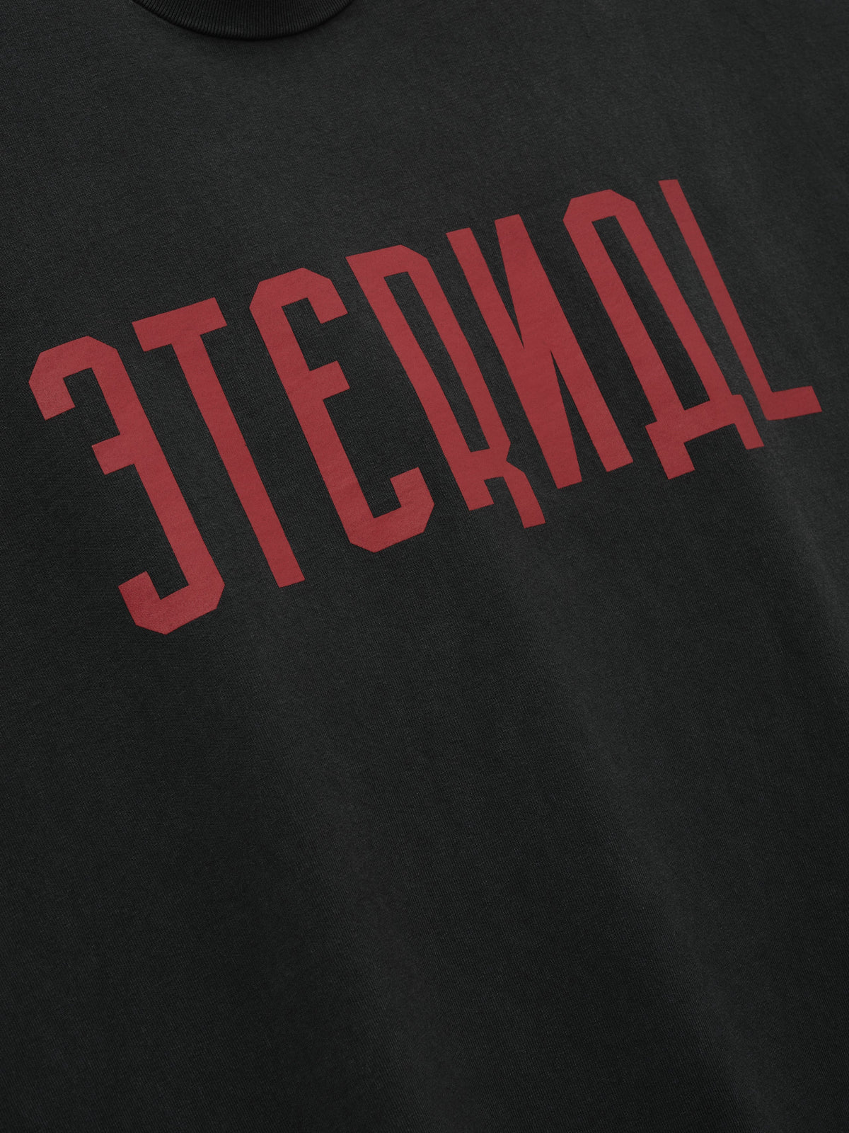 Eternal Tee in black featuring bold red Eternal lettering across the chest shown in close detail as Tops