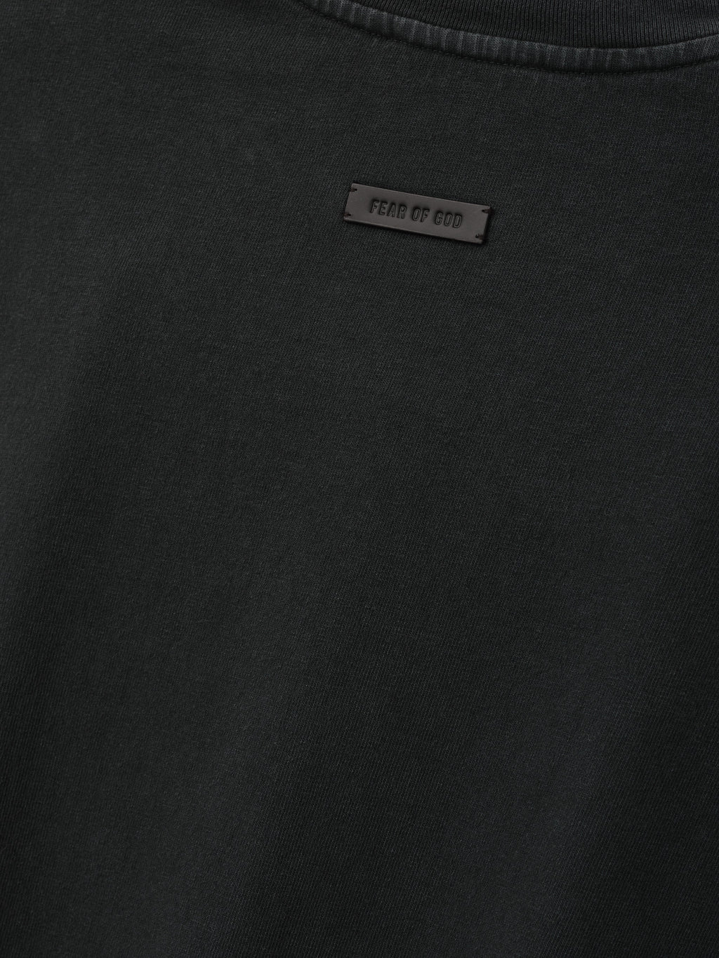 Eternal Tee in black shown in close detail with a tonal Fear of God label at the chest and ribbed crew neckline as Tops