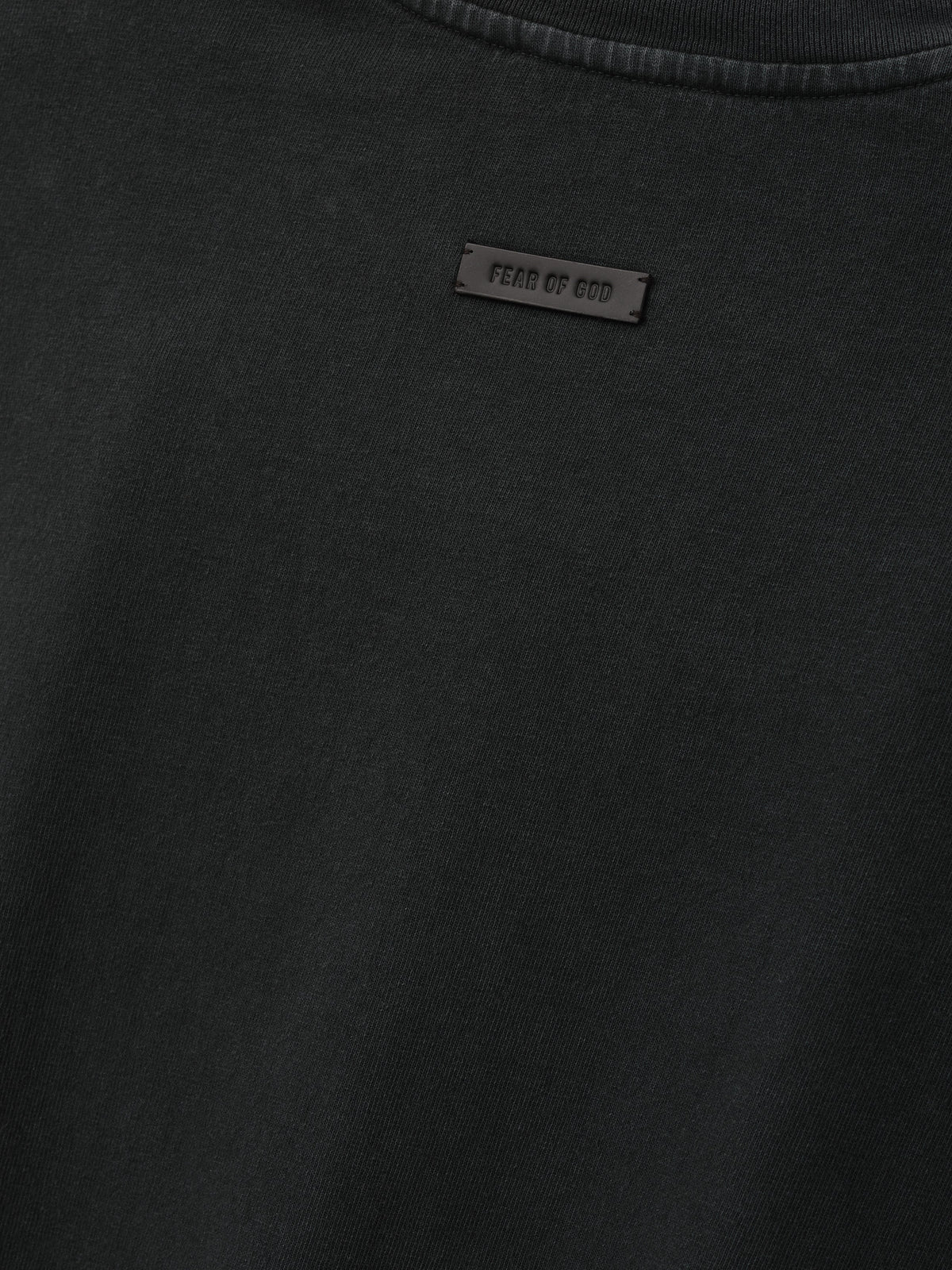 Eternal Tee in black shown in close detail with a tonal Fear of God label at the chest and ribbed crew neckline as Tops