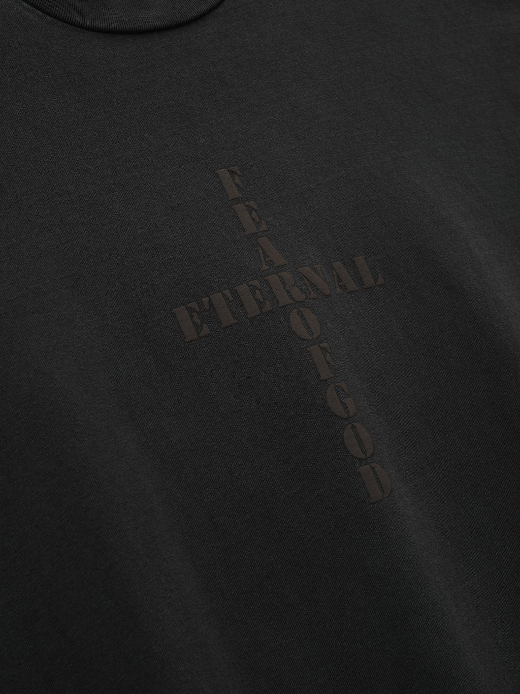 Cross Long Sleeve Tee in black with a subtle tonal Fear of God cross graphic and vertical lettering shown in close detail as Tops