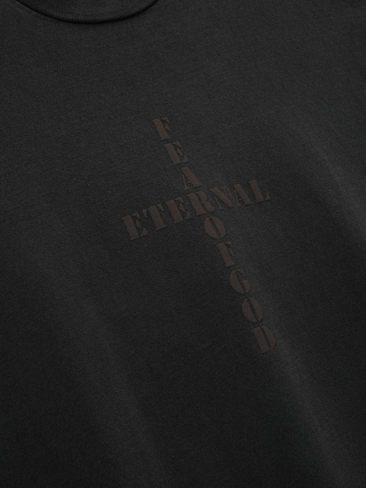 Cross Long Sleeve Tee in black with a subtle tonal Fear of God cross graphic and vertical lettering shown in close detail as Tops