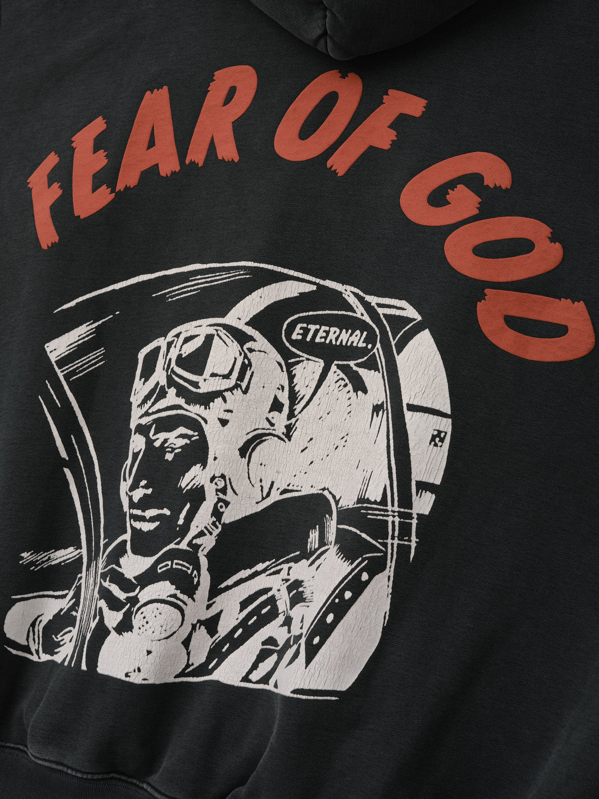 Flight Hoodie in black featuring red Fear of God lettering and a white vintage astronaut graphic with Eternal helmet detail shown in close detail as Tops