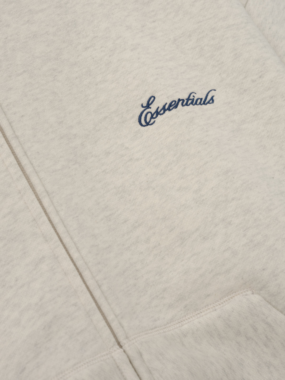 Signature Classic Zip Up Hoodie in light gray with navy Essentials chest logo and detailed kangaroo pocket stitching shown in close up as Tops
