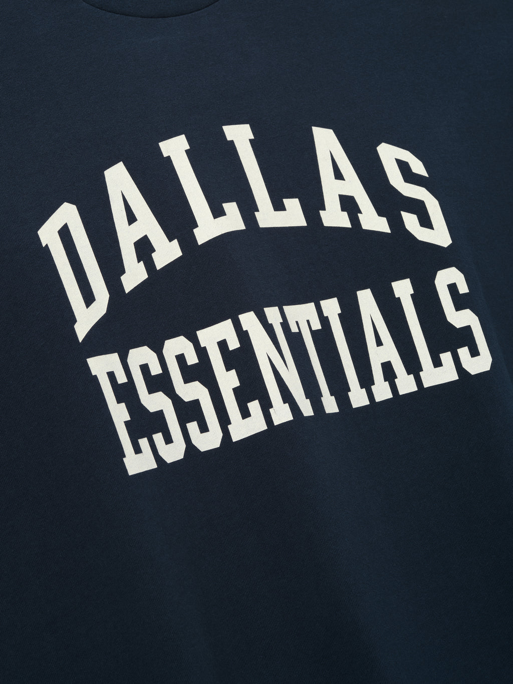 Cowboys Merch Tee navy short sleeve T shirt with bold white Dallas Essentials collegiate lettering shown in a close up Tops product view