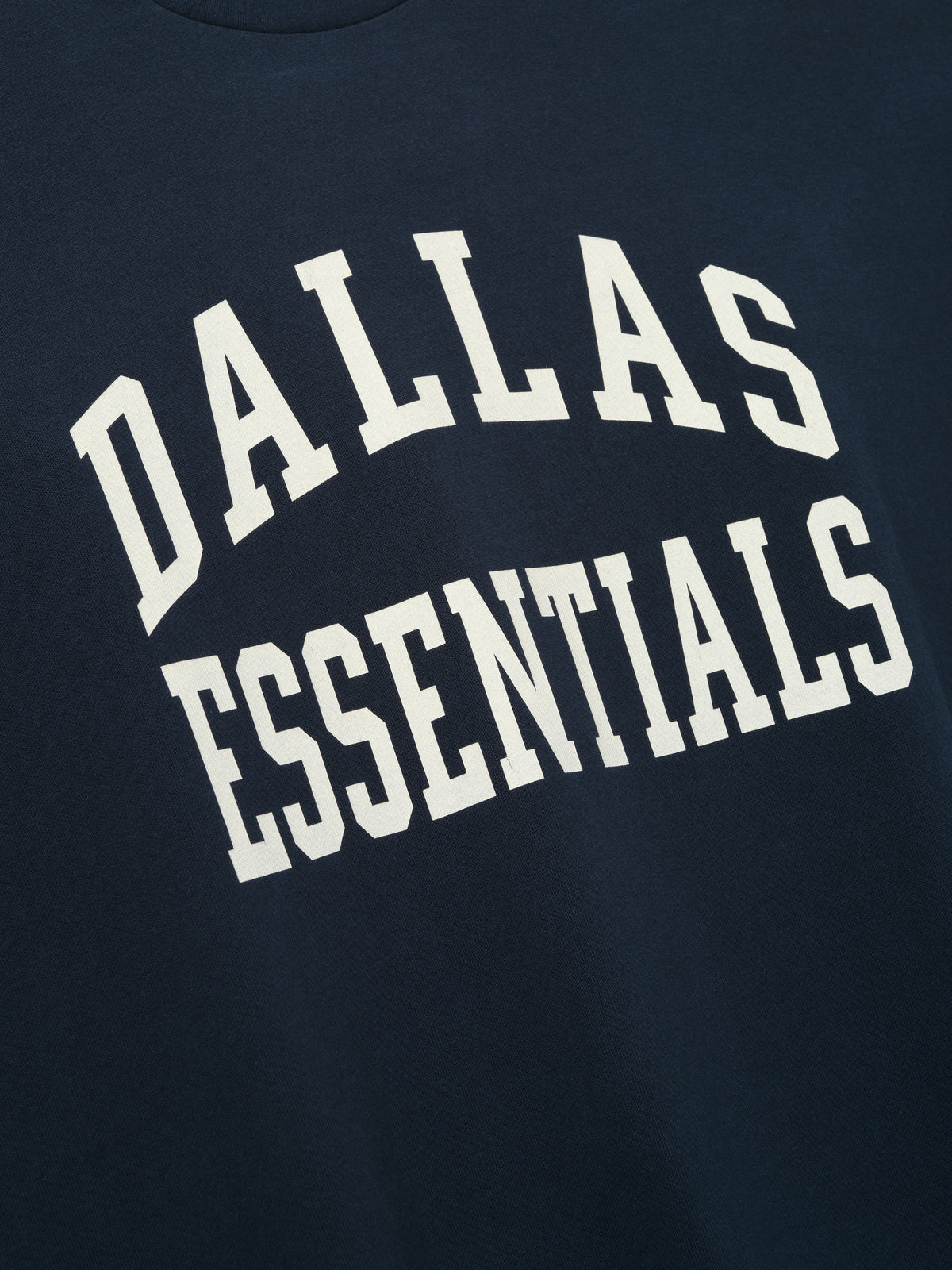Cowboys Merch Tee navy short sleeve T shirt with bold white Dallas Essentials collegiate lettering shown in a close up Tops product view