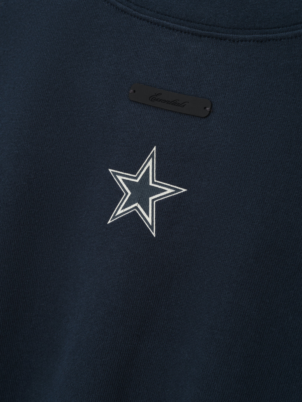 Cowboys Merch Tee navy fabric close up featuring a white outlined star emblem and black chest tag in a detailed Tops product view